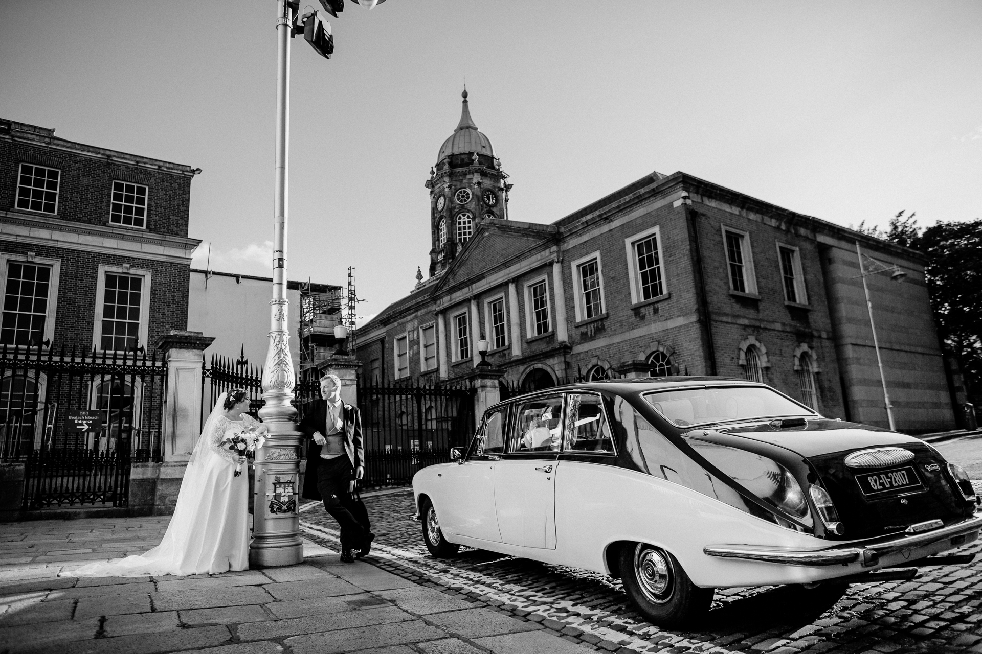 Bride and groom sharing a candid moment next to a vintage car in Dublin city – captured by a Dublin Wedding Photographer