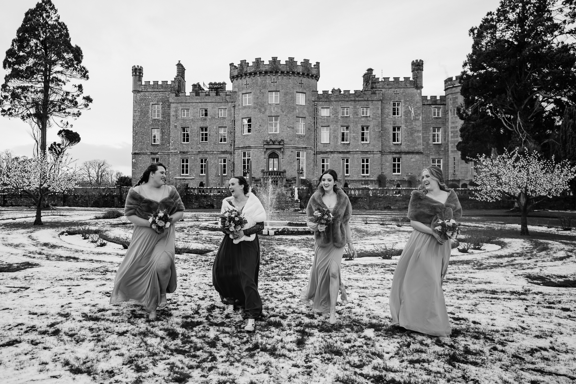 Bridal party walking toward the camera in front of Markree Castle, captured in black and white.