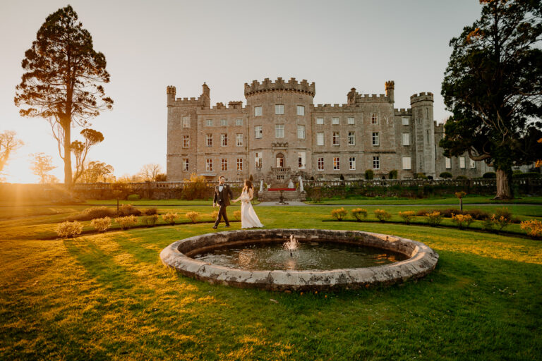 Bride and groom walking hand in hand at sunset in front of Markree Castle during a wedding in Ireland