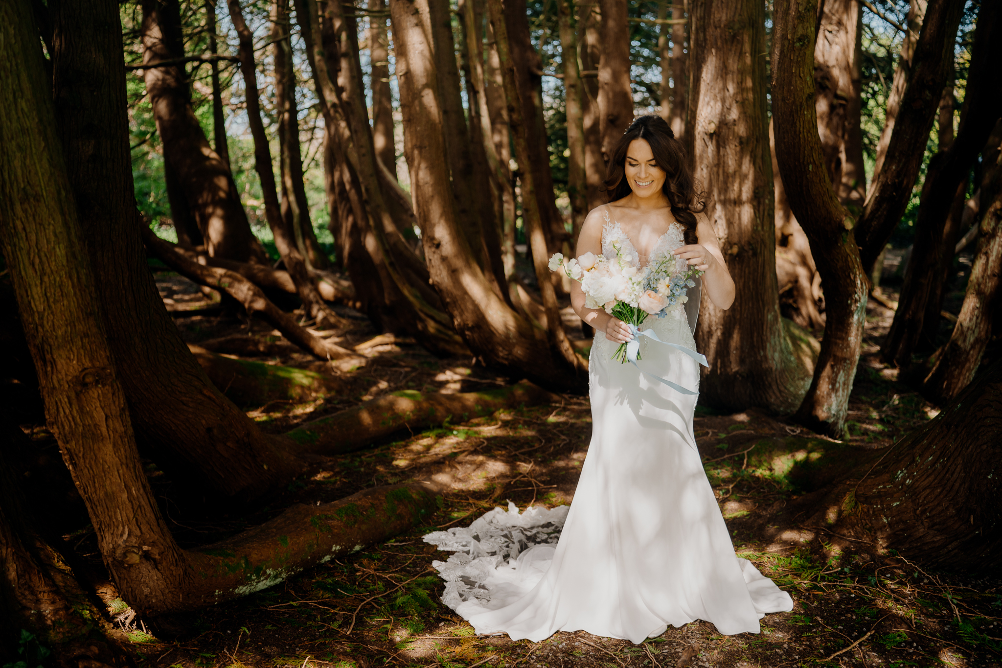 Bride standing in the woodland near Markree Castle, holding a fresh bouquet during a romantic wedding in Ireland