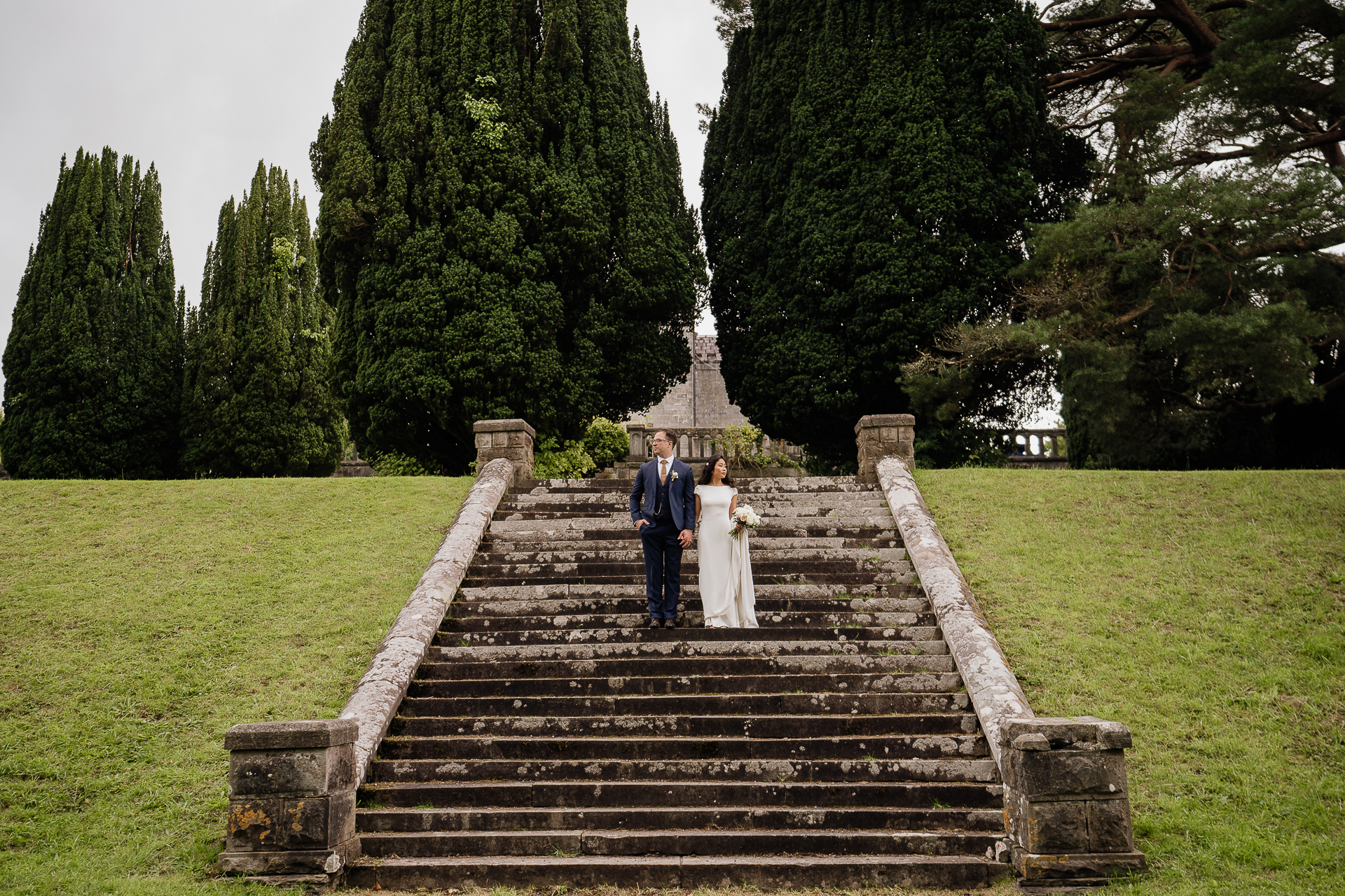 Bride and groom walking down grand outdoor staircase at Belleek Castle