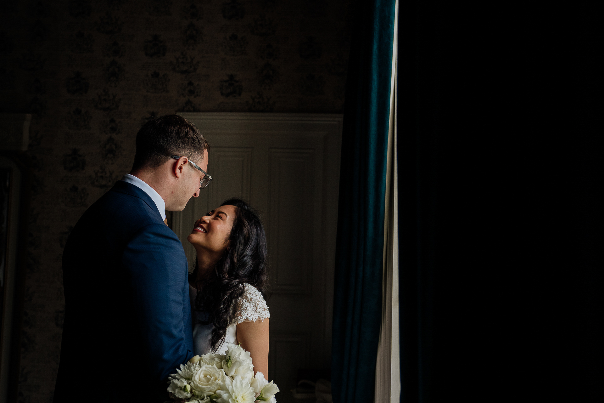 Bride and groom in a romantic indoor portrait at Belleek Castle with a flower bouquet