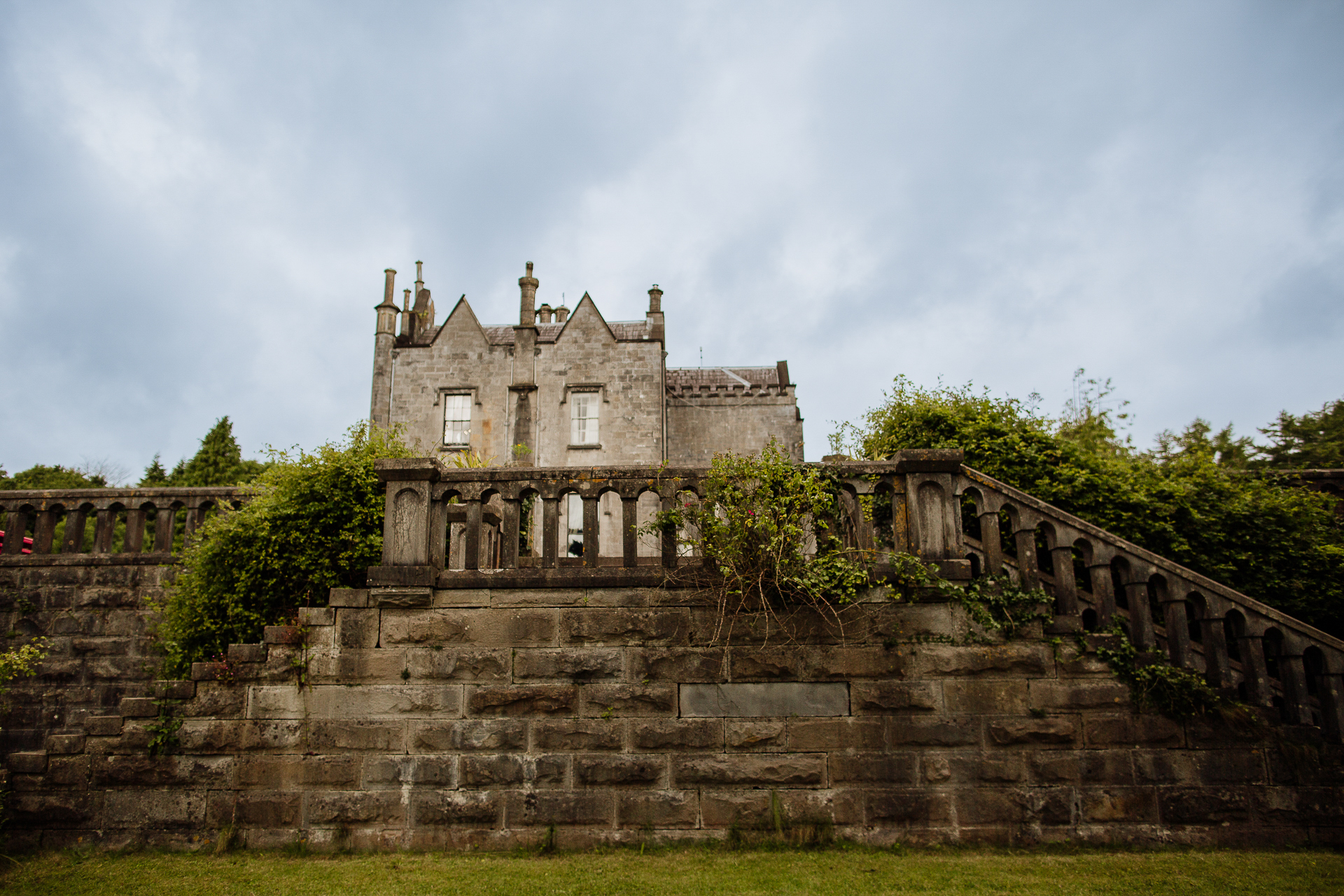 A wide view of Belleek Castle captured from below the grand stone stairs on a cloudy wedding morning. Belleek Castle Wedding inspiration for elegant Irish castle ceremonies.