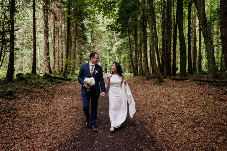 Bride and groom walking through the forest at Belleek Castle, captured during a romantic candid moment in Ireland.