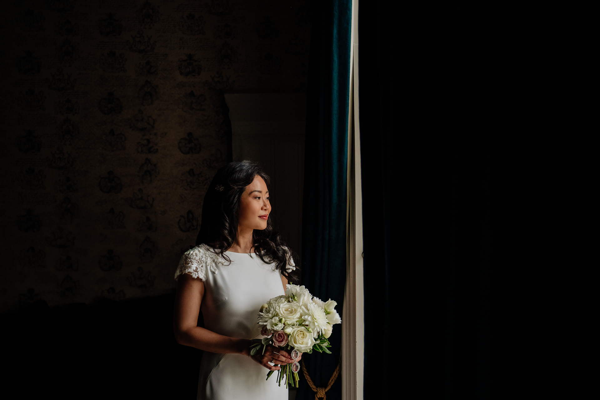 Bride holding her bouquet while standing near a window in Belleek Castle