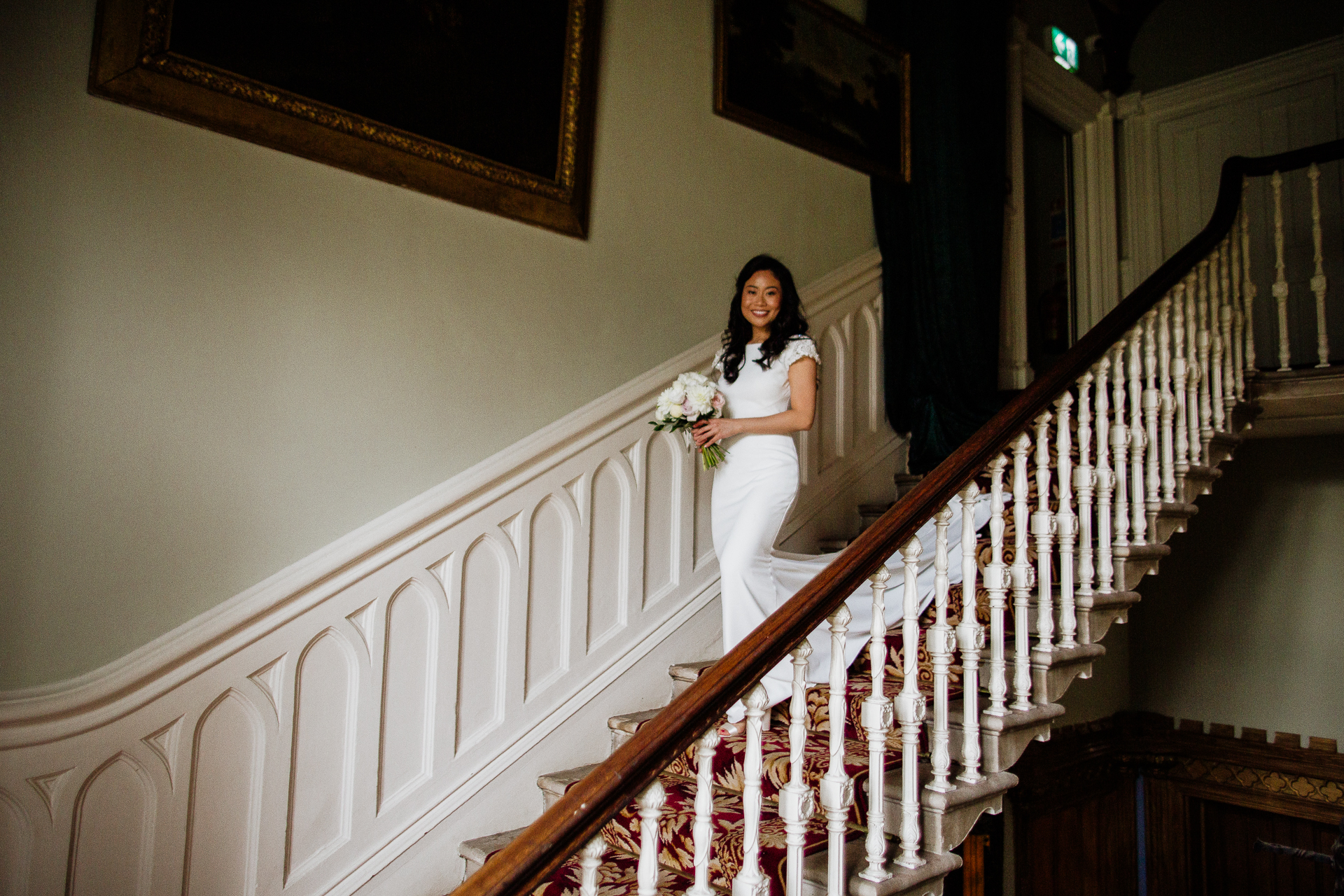 Bride walking down the staircase at Belleek Castle holding her bouquet