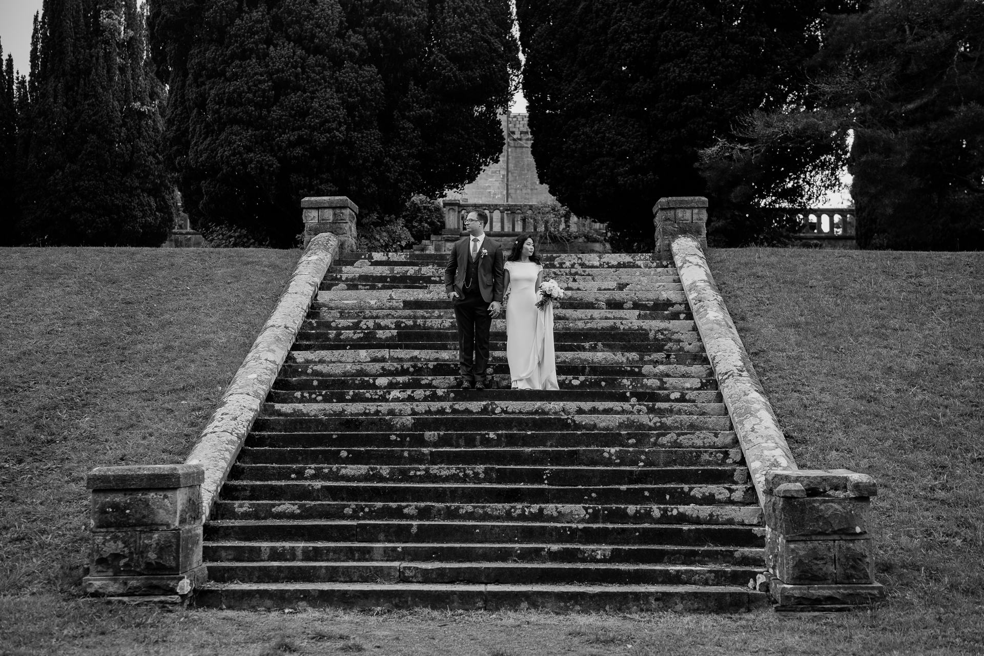 Black and white portrait of a bride and groom standing together on the stone staircase at Belleek Castle