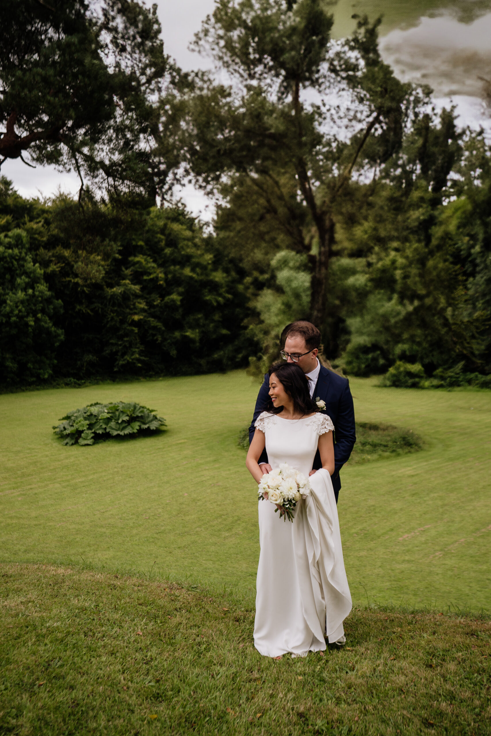 Bride and groom walking across the garden lawn at Belleek Castle