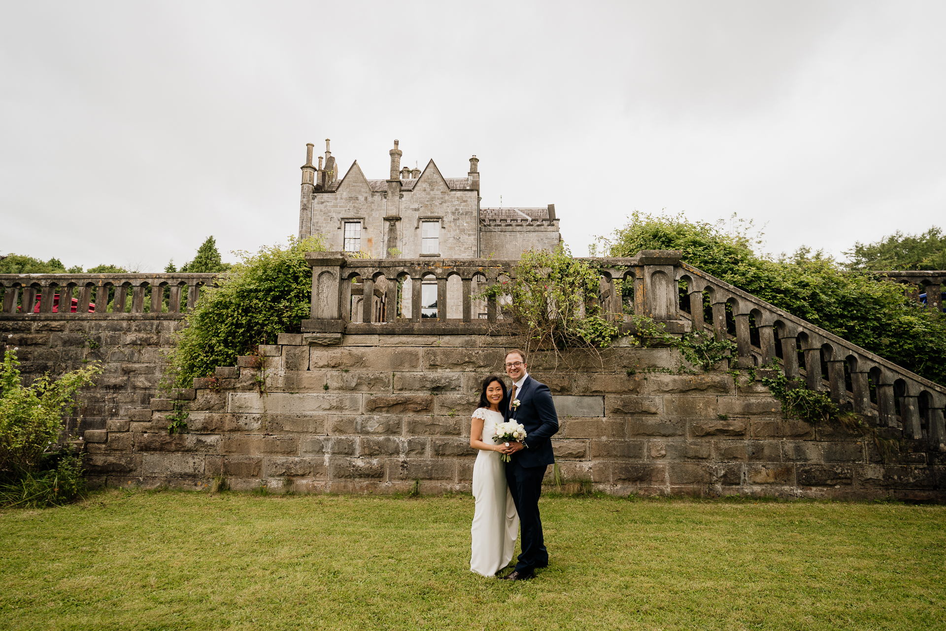 Bride and groom posing in front of the stone terrace at Belleek Castle