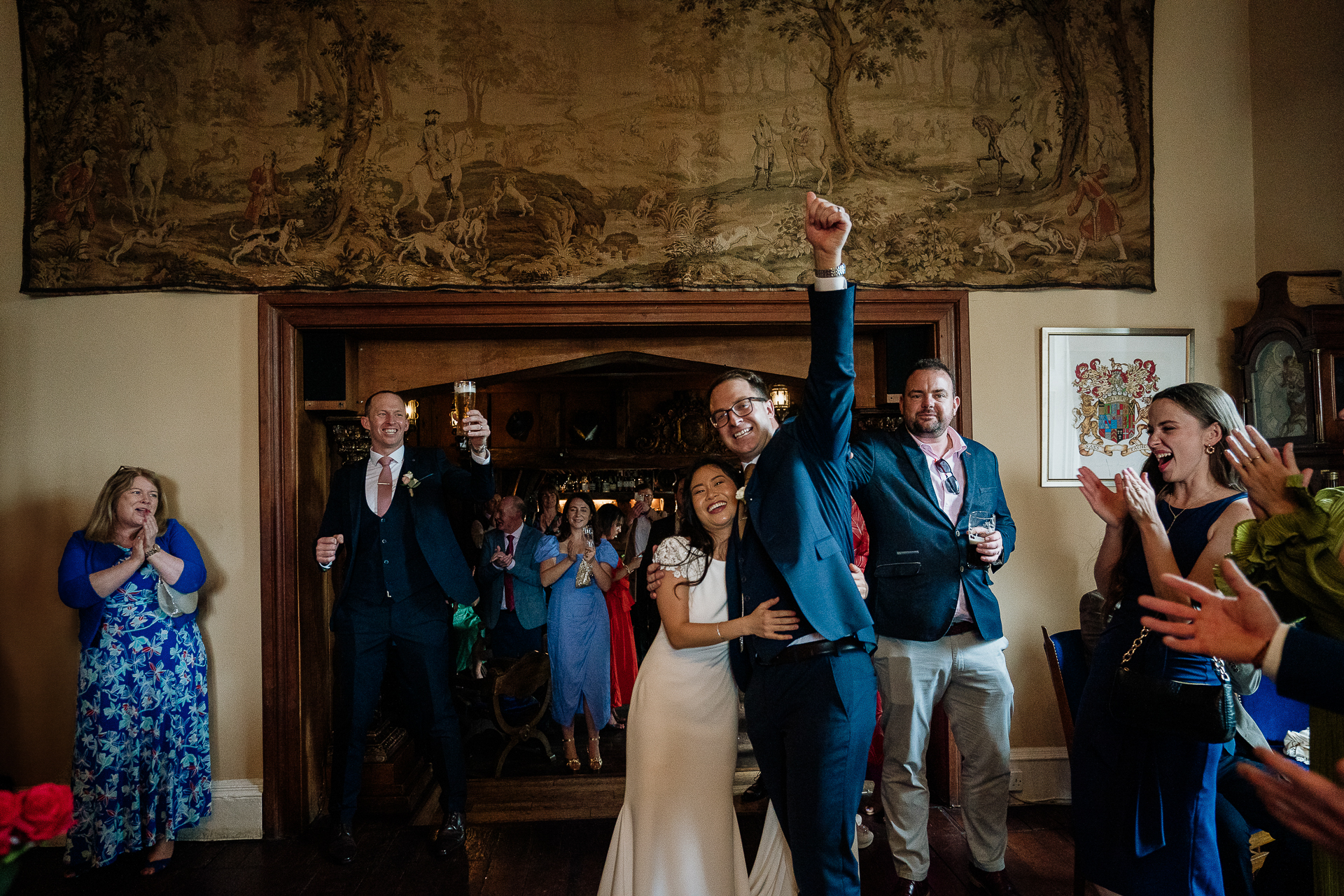 Bride and groom entering Belleek Castle dining hall while guests cheer joyfully