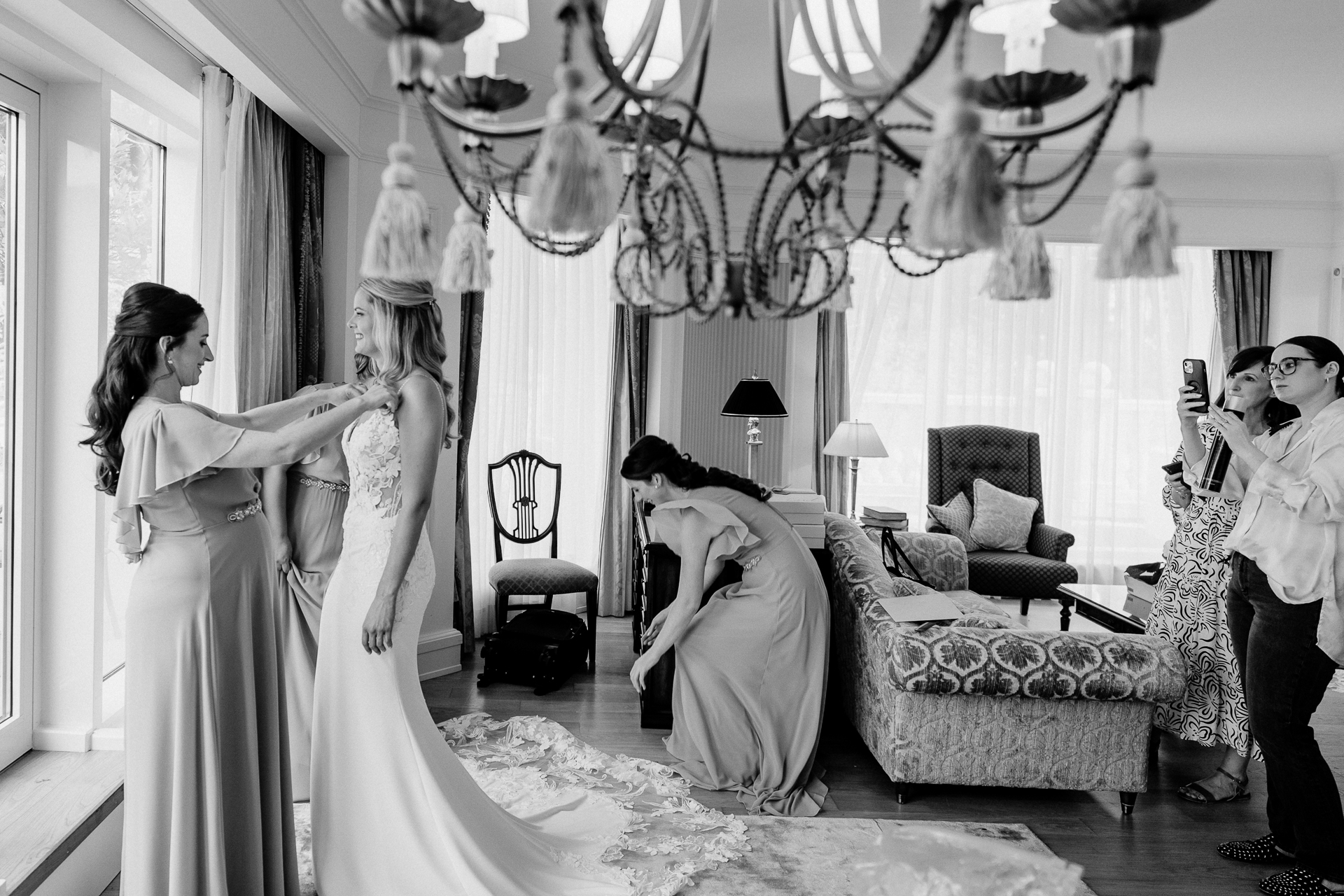 Black and white wedding photo of the bride putting on her dress, taken at Powerscourt House by a Dublin Wedding Photographer