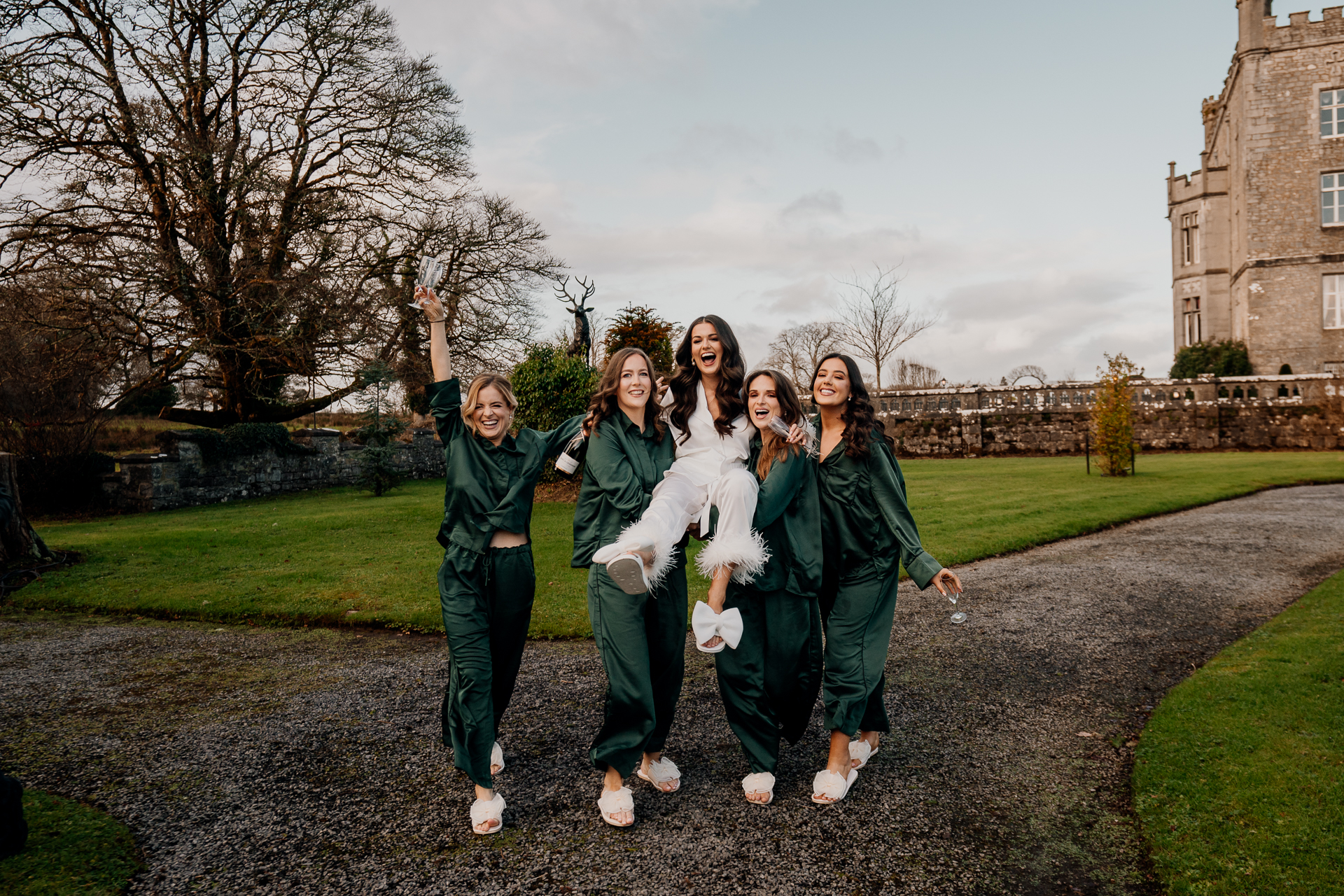 Bridesmaids laughing and walking together in the garden at Markree Castle, wearing green robes during wedding morning preparations.