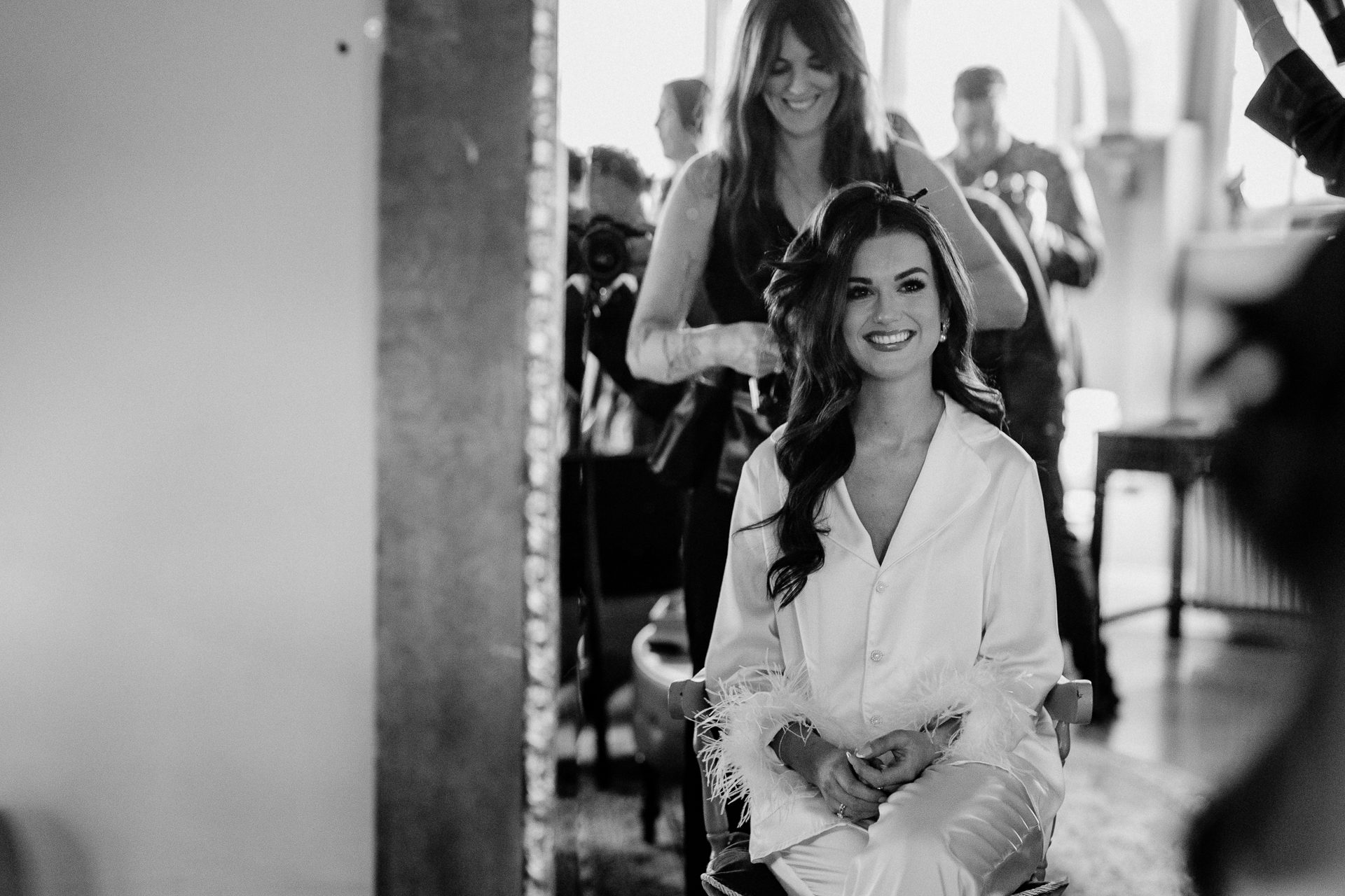Black and white photo of the bride sitting in the Butler’s Kitchen at Markree Castle, surrounded by bridesmaids during wedding morning preparations.
