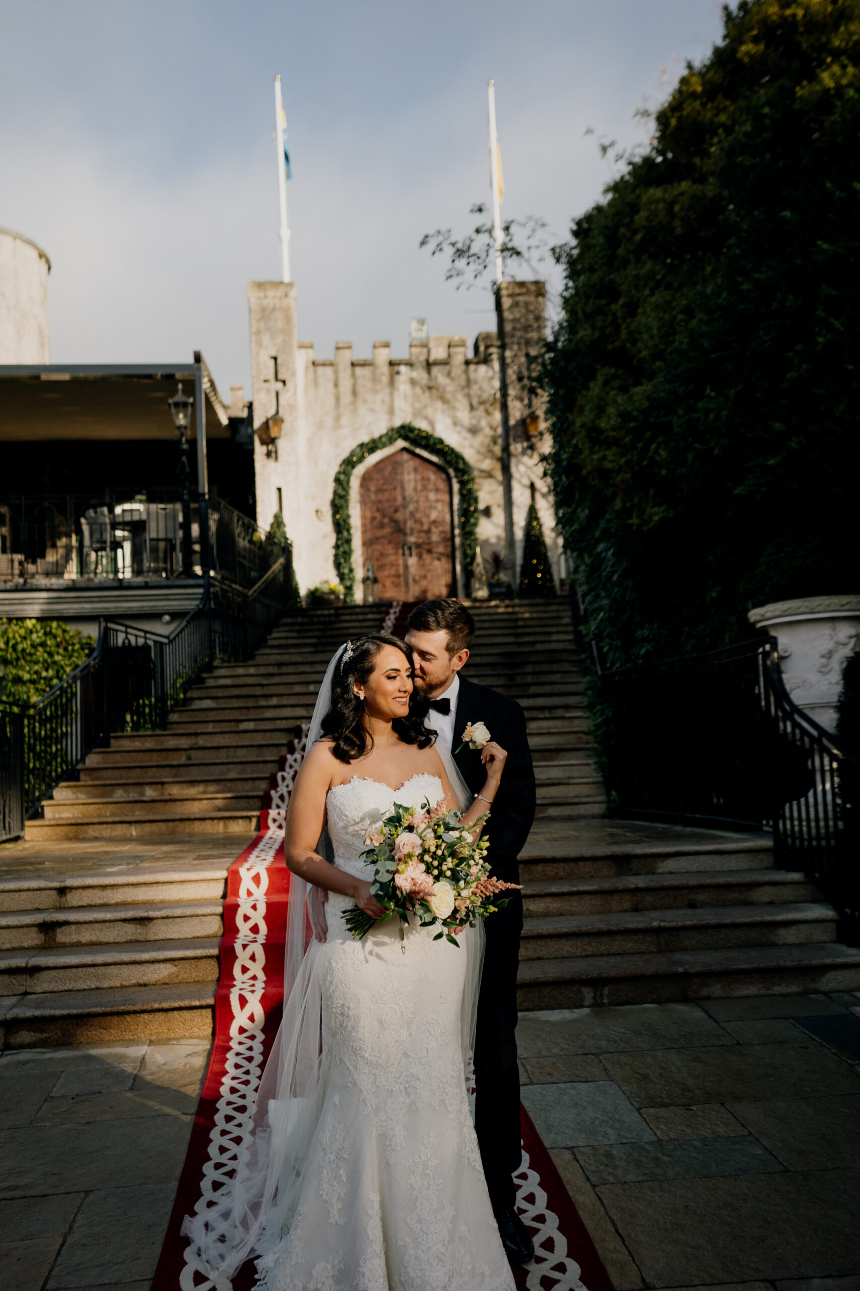 Bride and groom walking down the iconic staircase of Cabra Castle, surrounded by greenery