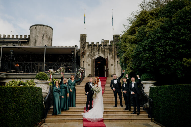 Bride and groom with their bridal party on the stone steps of Cabra Castle during a wedding celebration