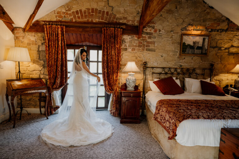 Bride getting ready at Cabra Castle, standing in front of a vintage window in her wedding gown, captured by a Castle Wedding Photographer Ireland