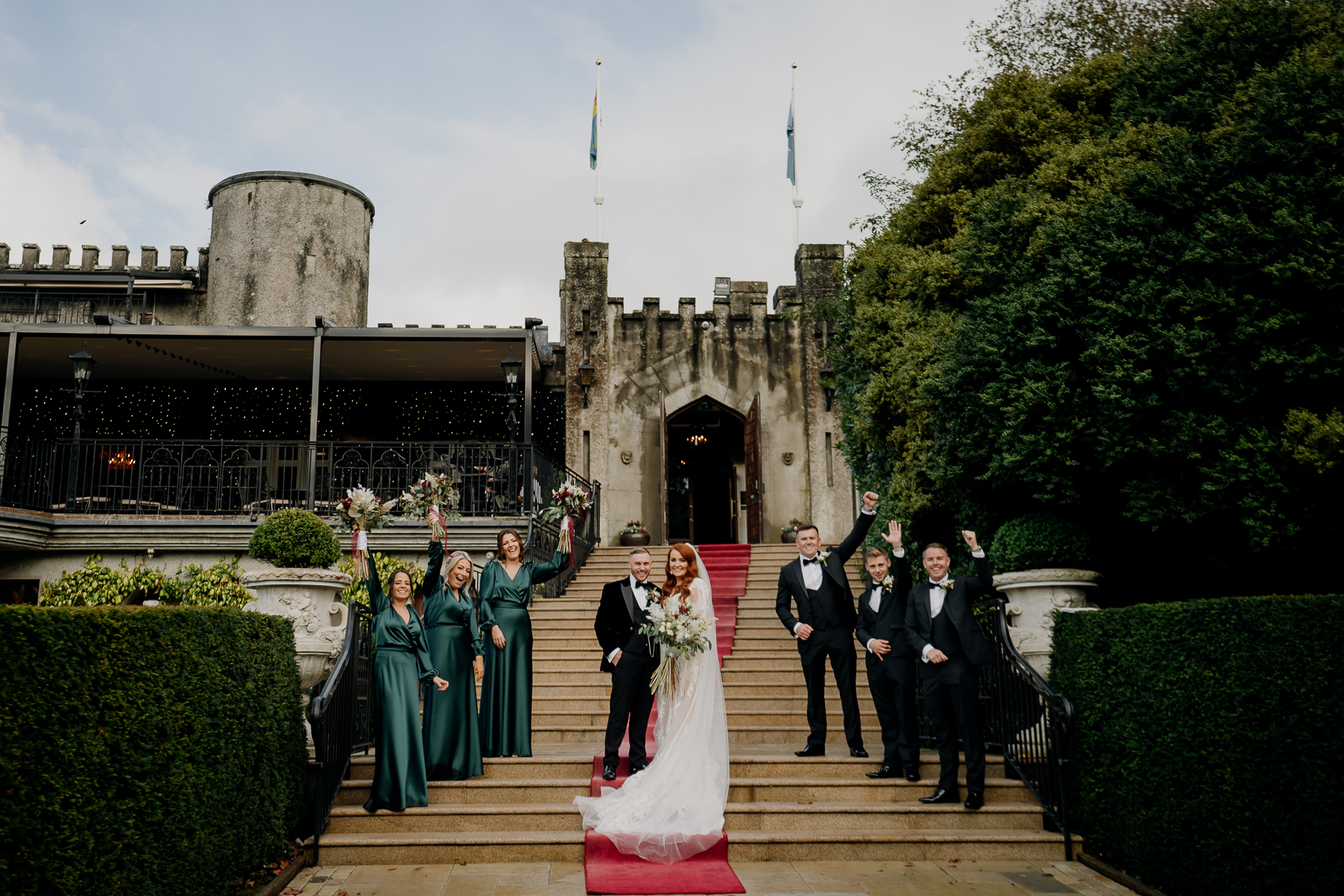 Bride walking up the red carpet steps to Cabra Castle, greeted by guests and bridal party.