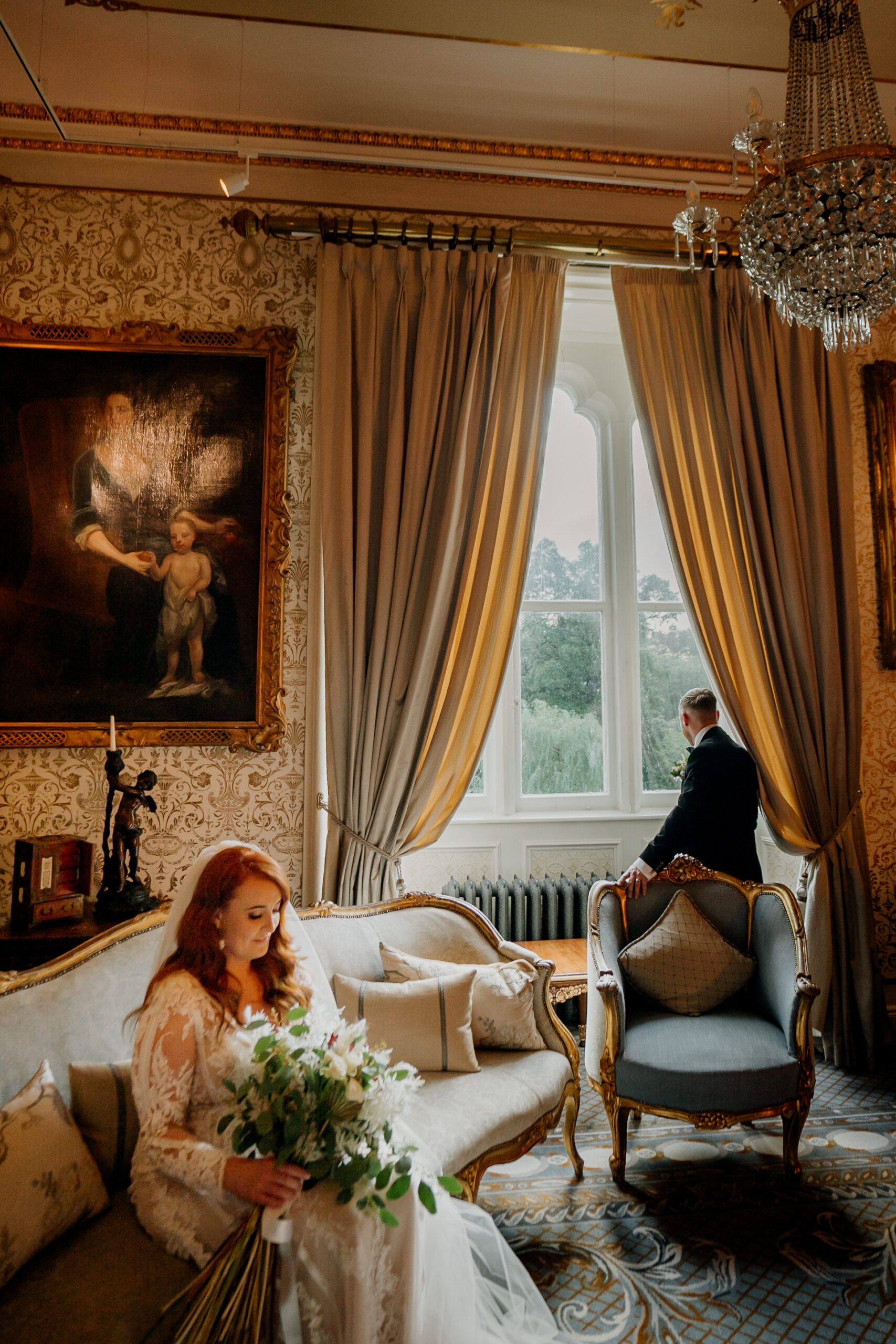 Bride sitting in the drawing room of Cabra Castle, holding a bouquet and surrounded by elegant decor.