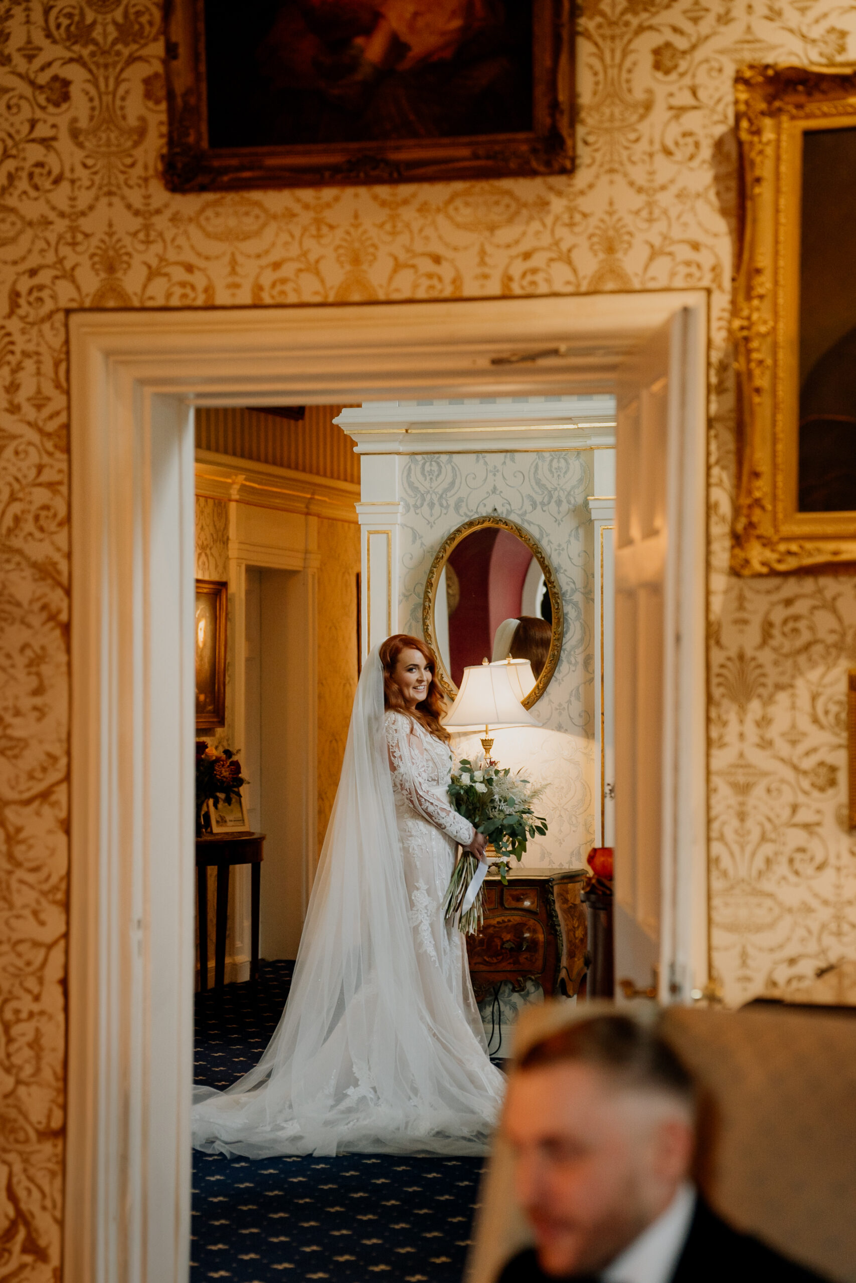 Bride walking through the golden hallway of Cabra Castle with bouquet in hand.