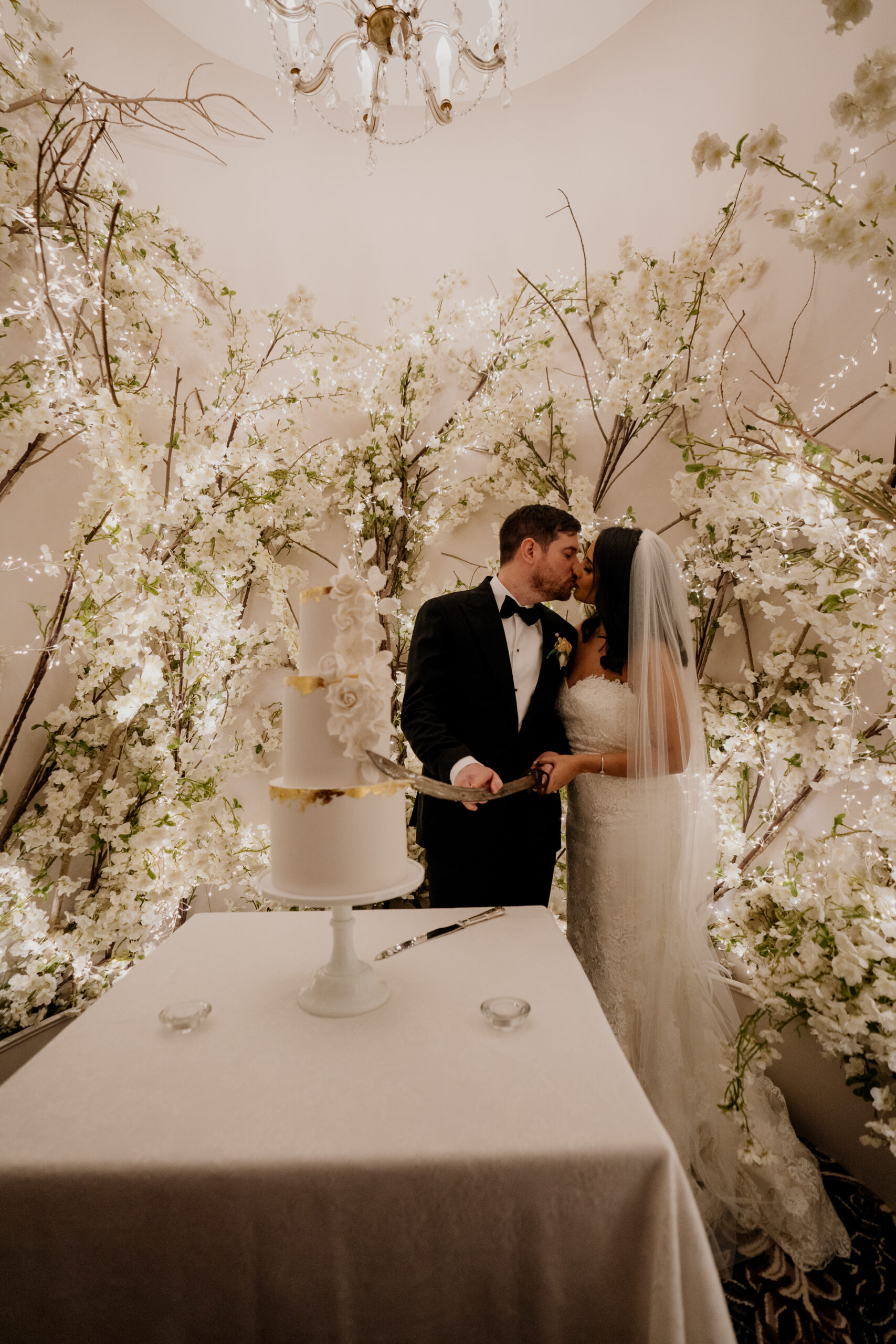 Bride and groom cutting their wedding cake under floral arch at Cabra Castle.