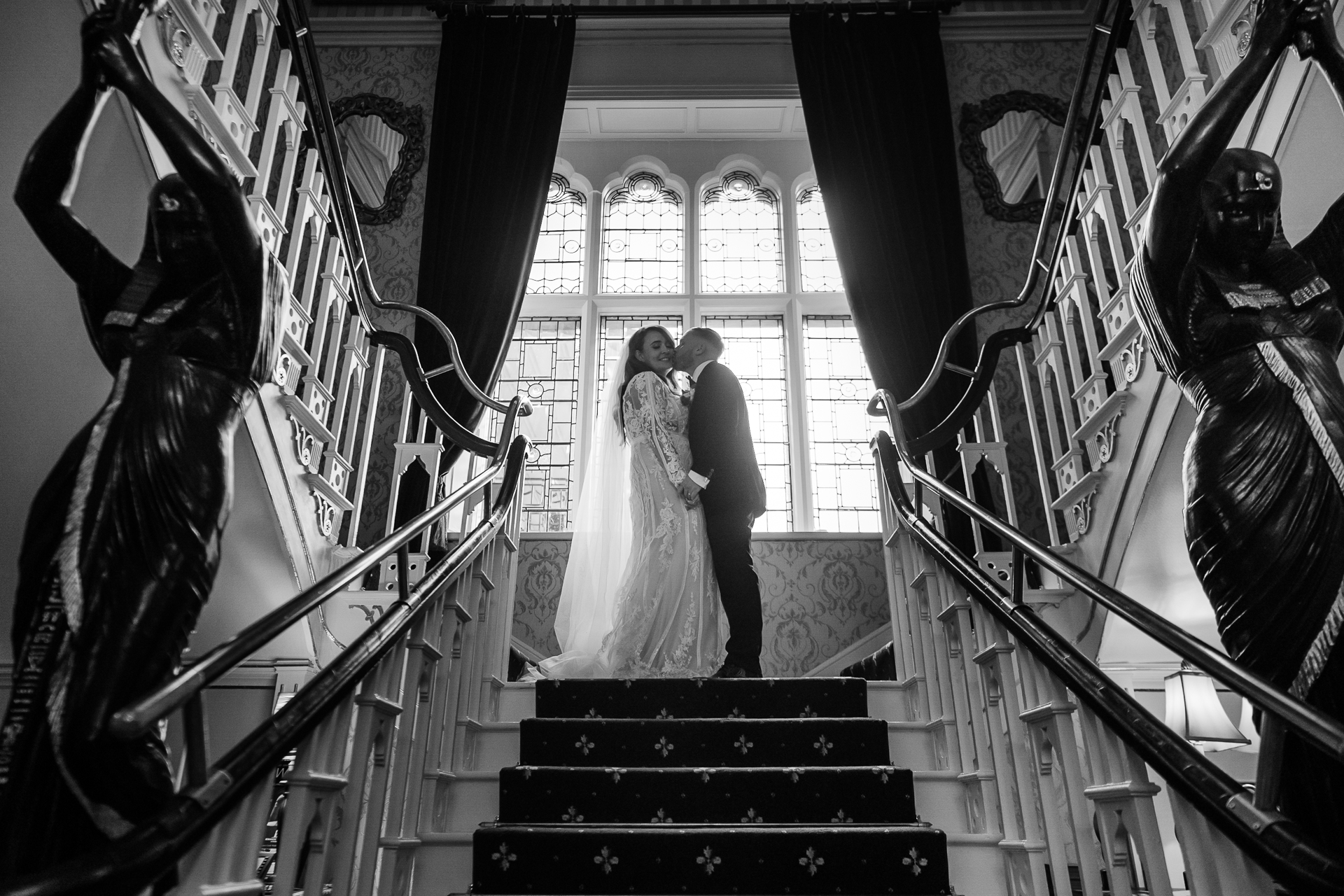 Bride and groom kiss on the grand staircase of Cabra Castle – black and white photo