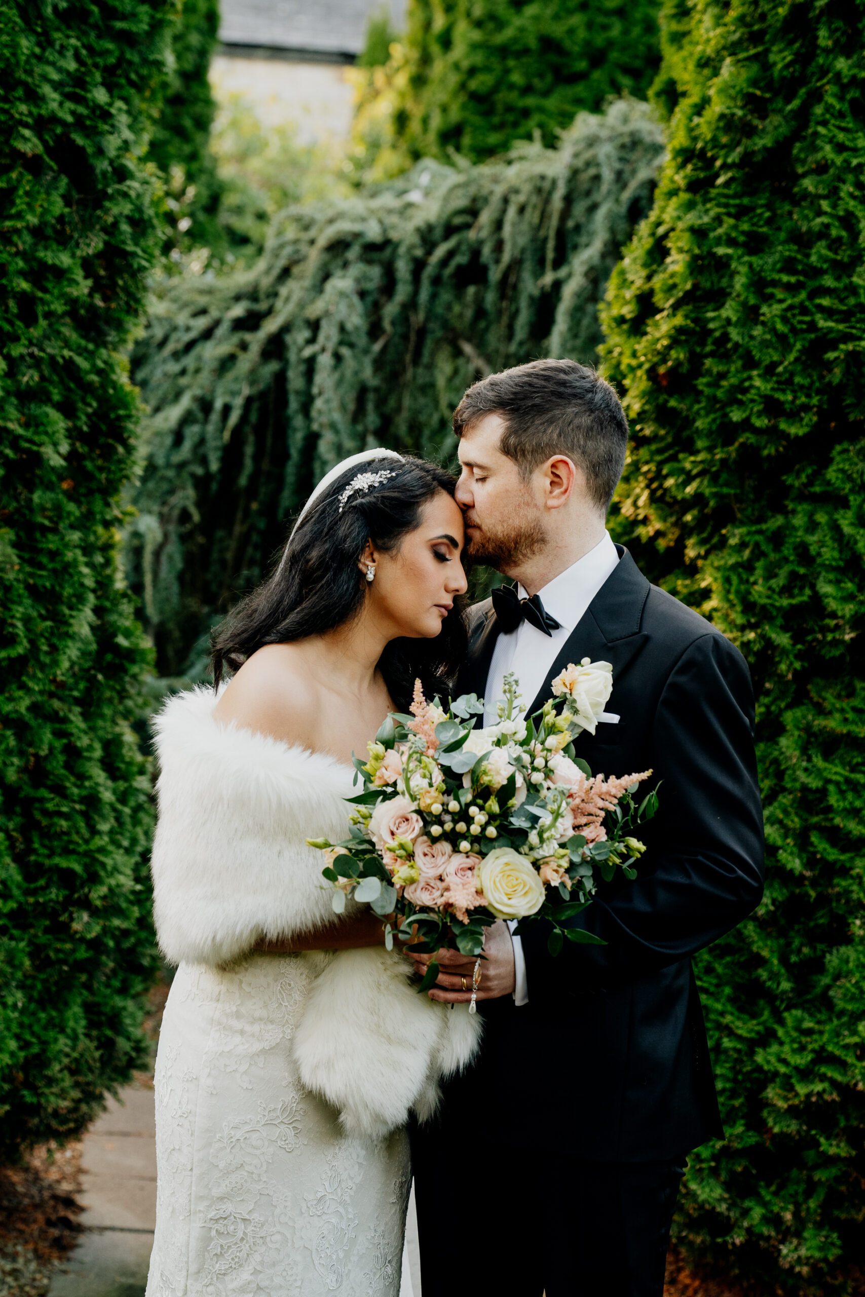 Bride and groom share a quiet kiss in the garden at Cabra Castle, surrounded by lush greenery.
