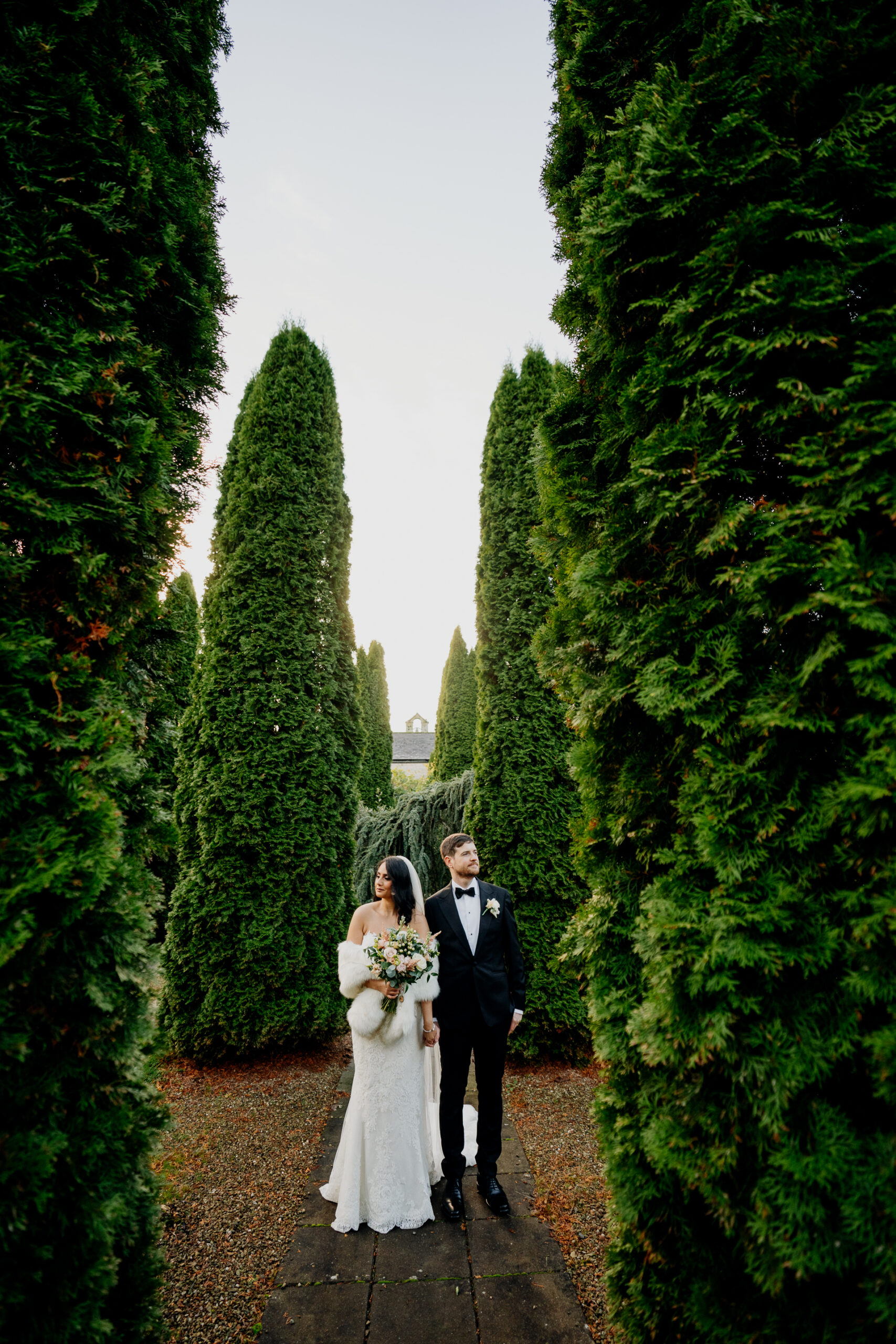 Bride and groom portrait between tall hedges in Cabra Castle’s garden.