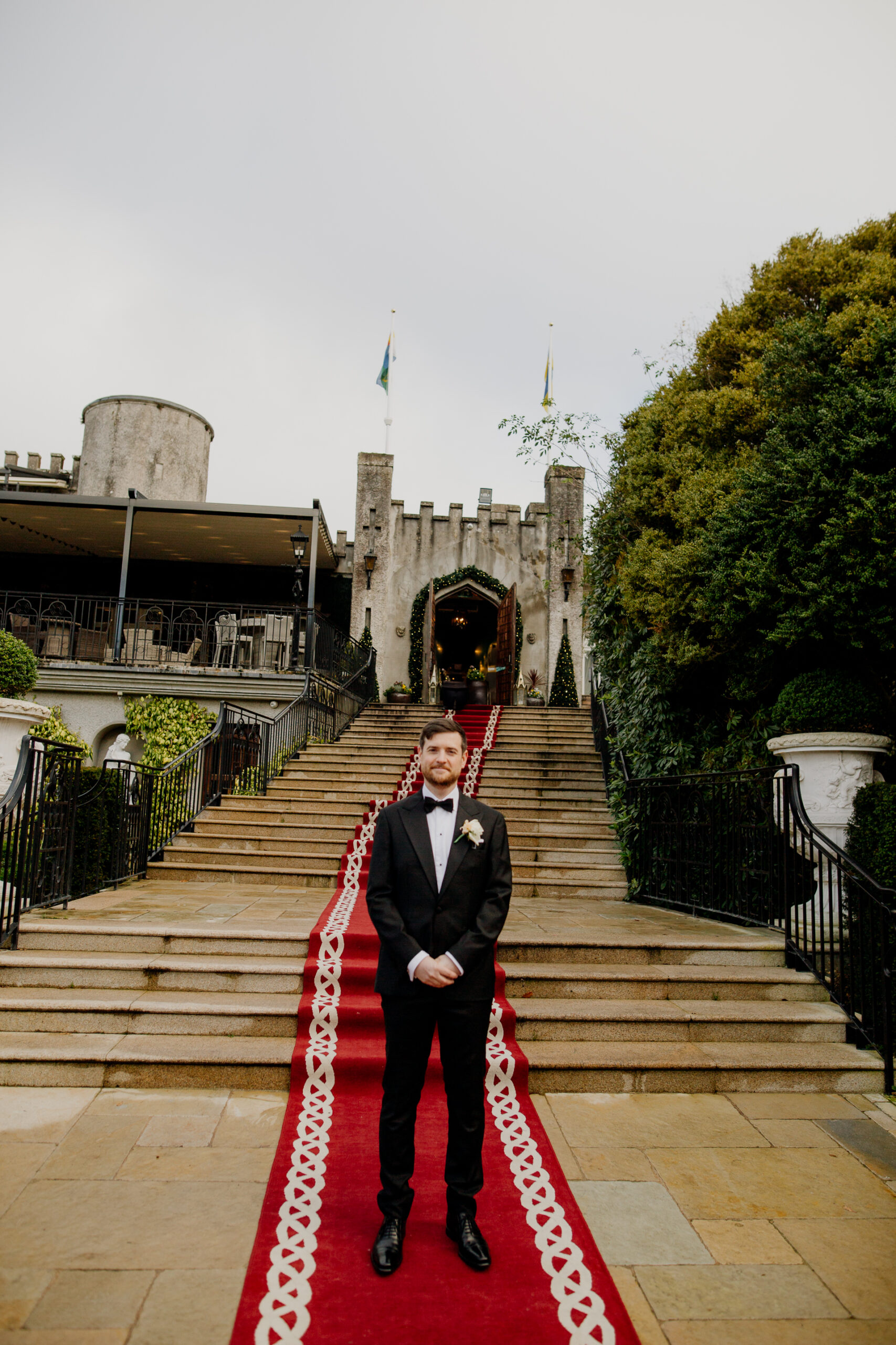 Groom standing alone on the red carpet in front of Cabra Castle before the First Look – elegant and emotional moment captured at this Irish castle wedding