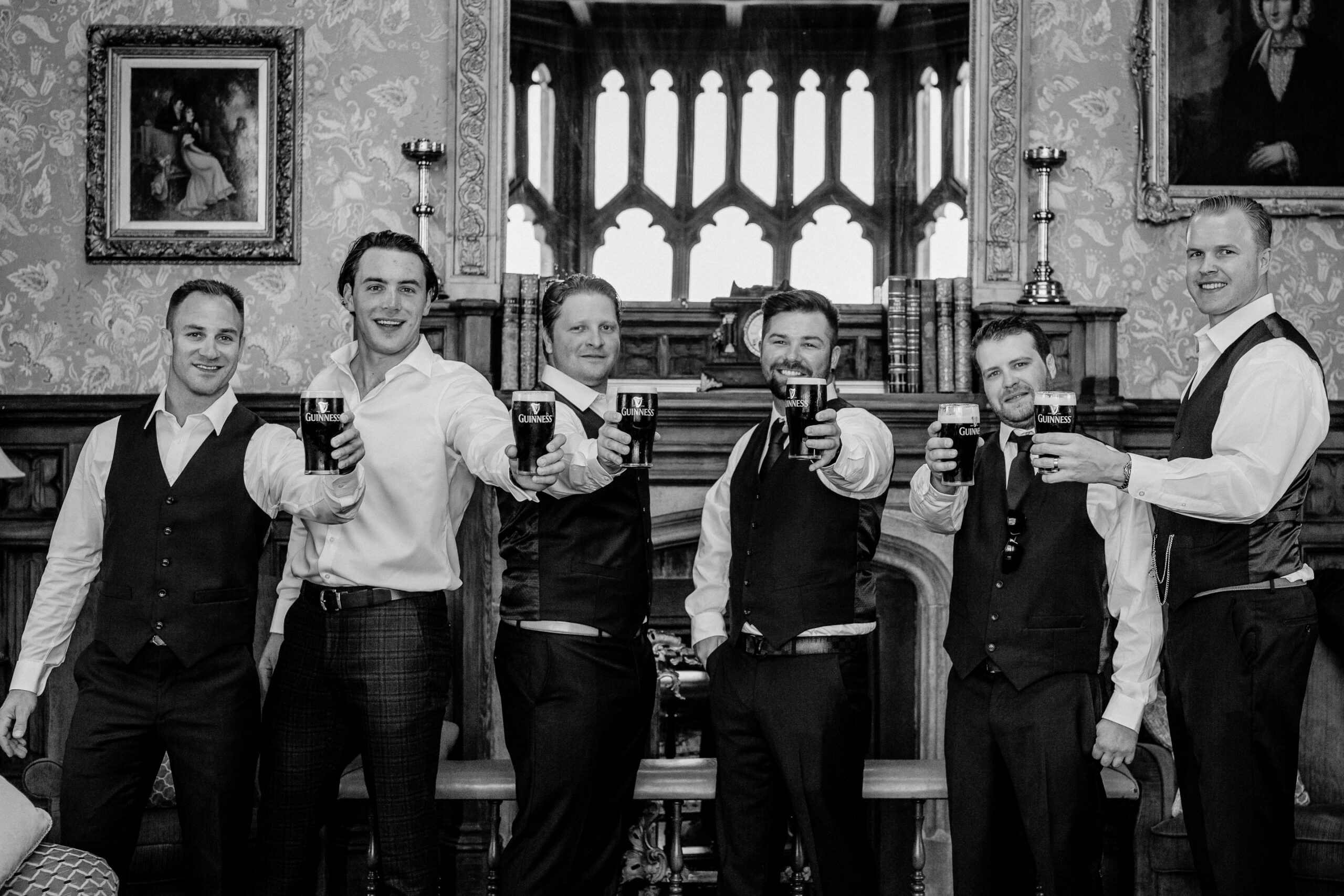 Groomsmen making a toast inside Markree Castle before the wedding – black and white candid moment