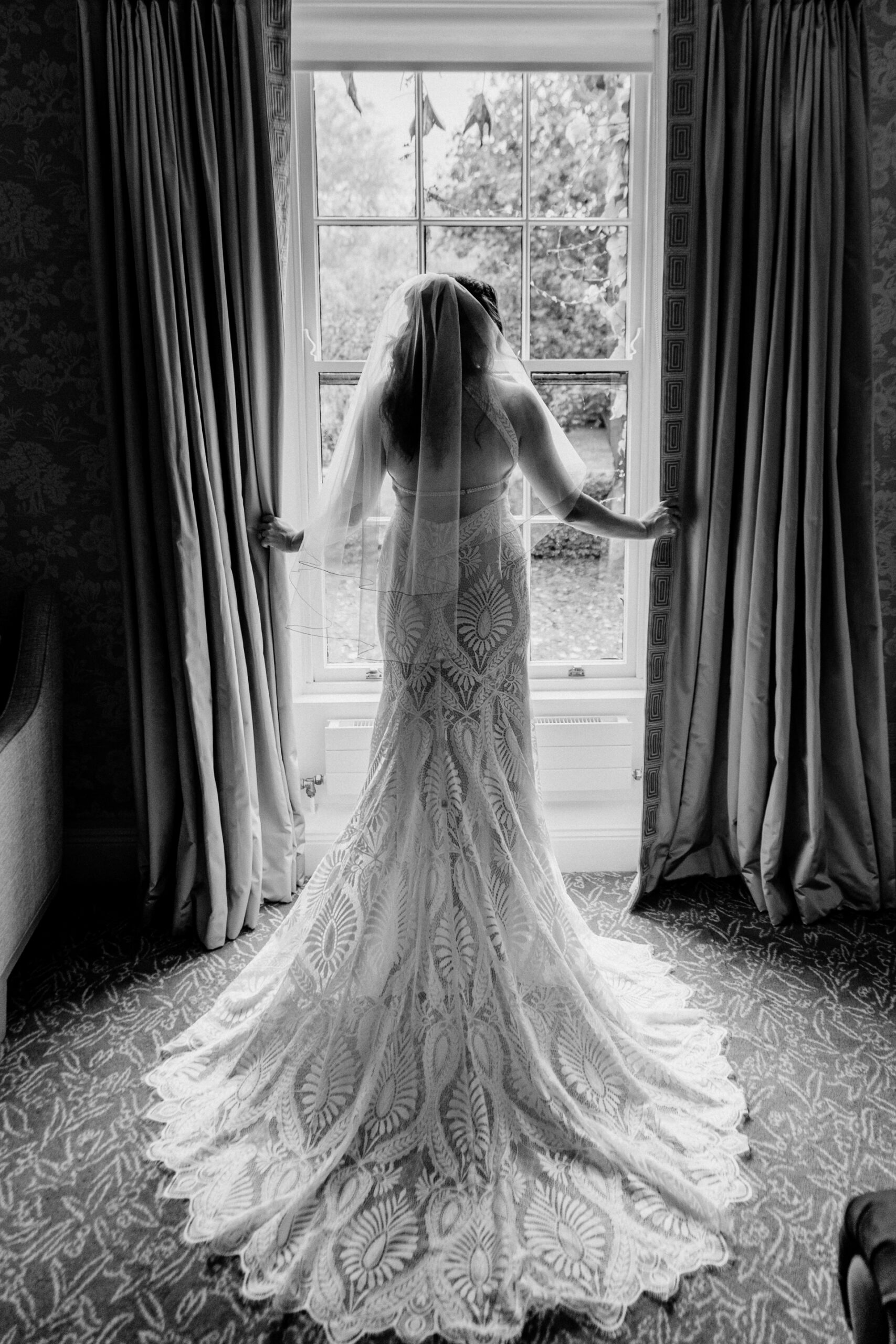 Back view of bride in lace gown standing in front of large window in Barberstown Castle
