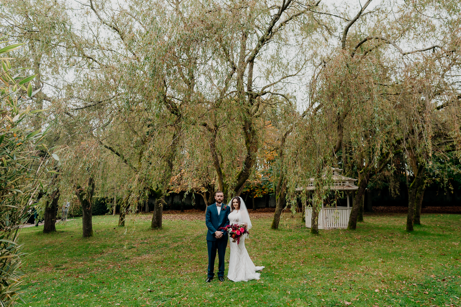 Bride smiling in soft window light with bold red bouquet at Barberstown Castle wedding