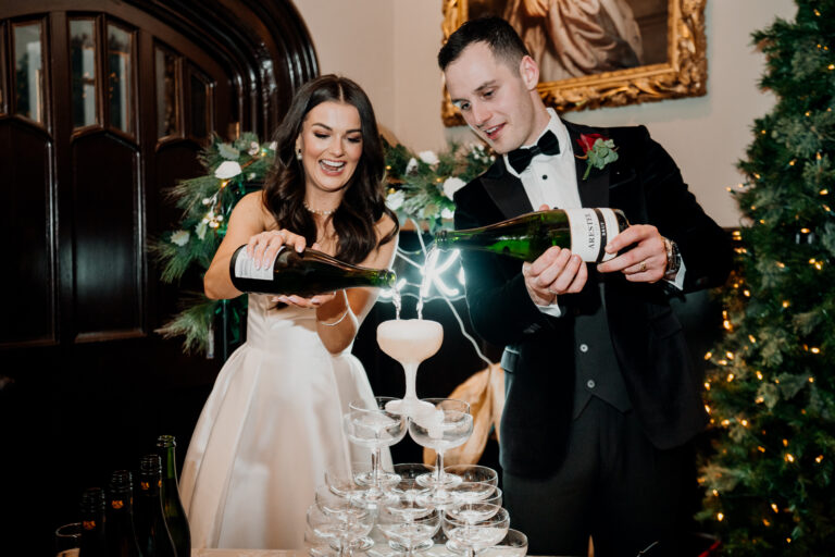 Bride and groom pouring champagne on a glass tower during a festive Markree Castle wedding reception captured by a Dublin Wedding Photographer