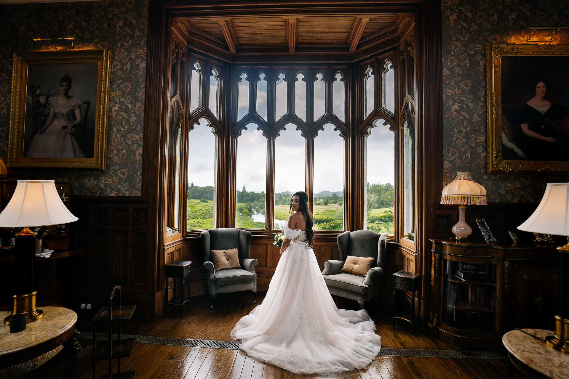 Bride standing in front of a tall arched window in the Billiard Room at Markree Castle, lit by natural window light.