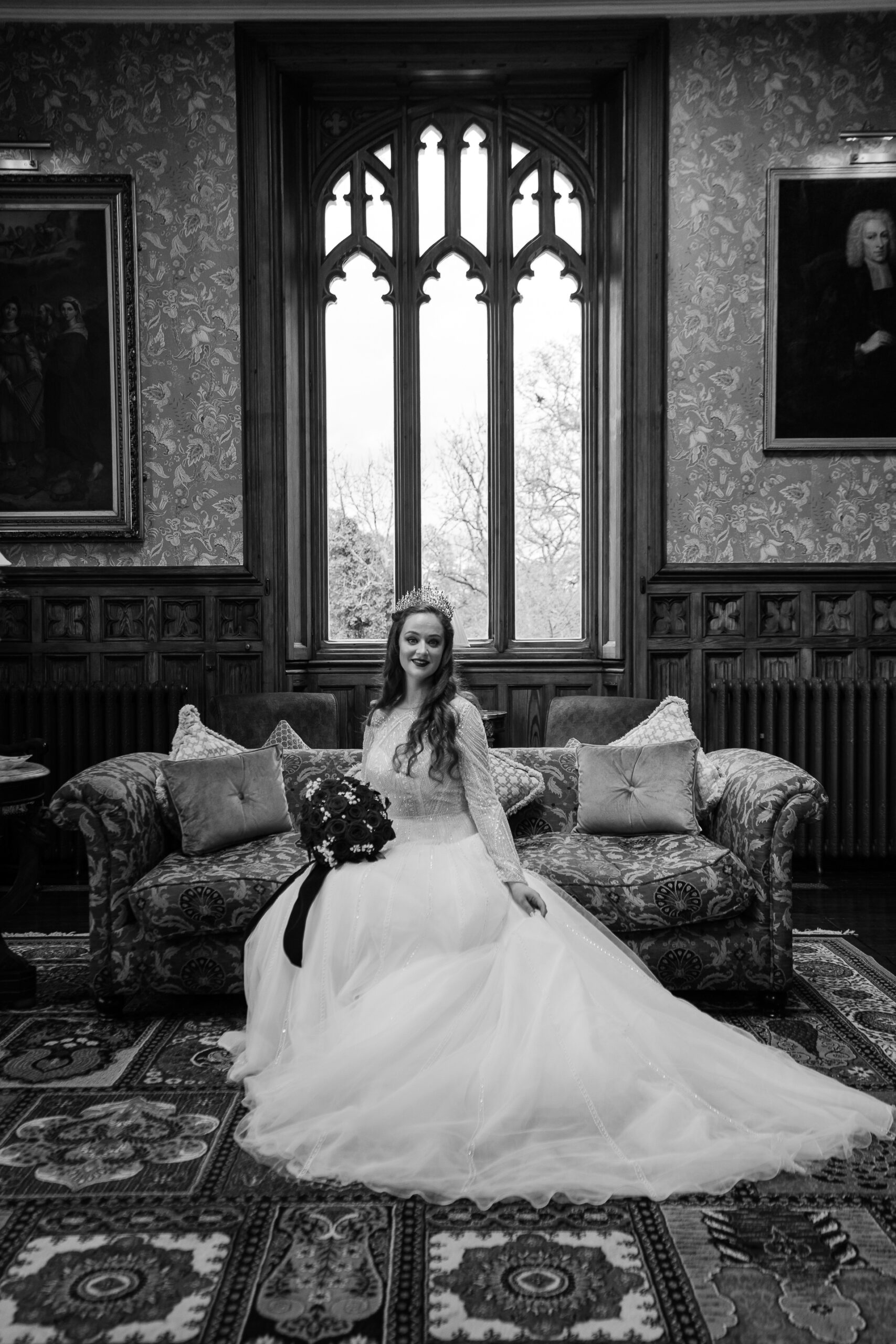 Black and white bridal portrait at Markree Castle, bride sitting on a vintage sofa by the window in the Billiard Room