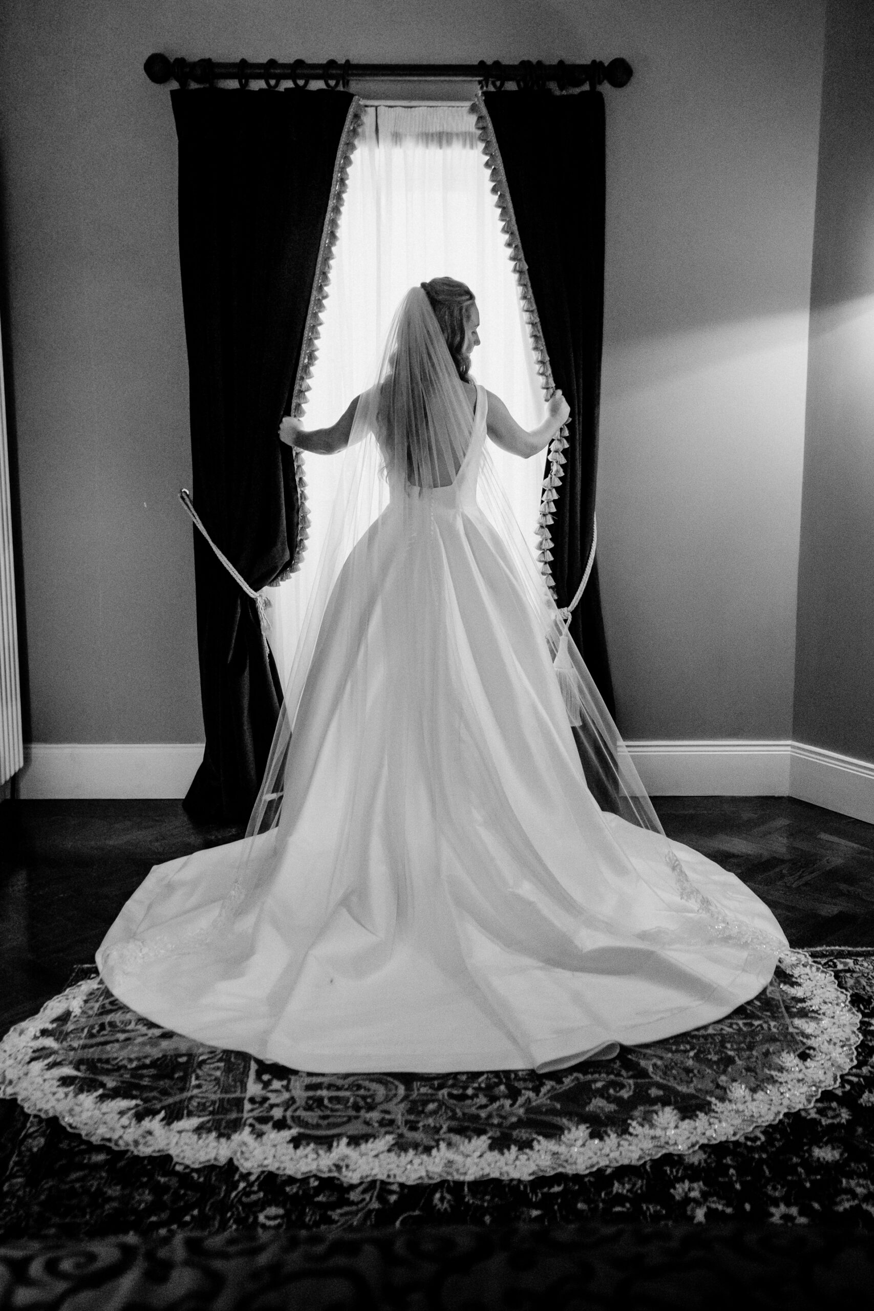Bridal portrait in black and white – Markree Castle bride standing by the window in her wedding dress.
