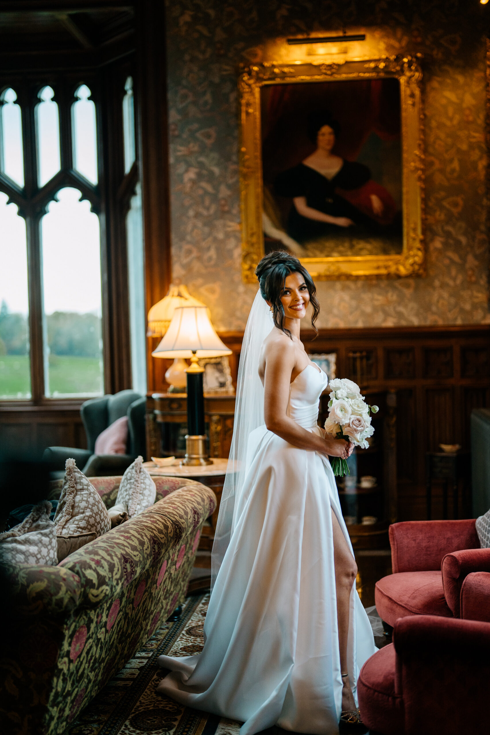 Elegant bride standing in the Billiard Room at Markree Castle, holding bouquet near window light