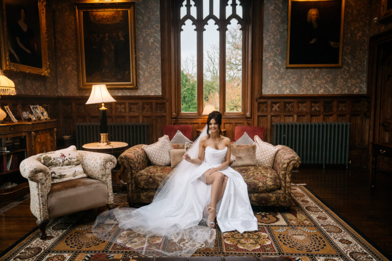 Bride sitting in a Victorian-style room at Markree Castle, with elegant window light and a luxurious white gown – captured by a Destination Wedding Photographer in Ireland.