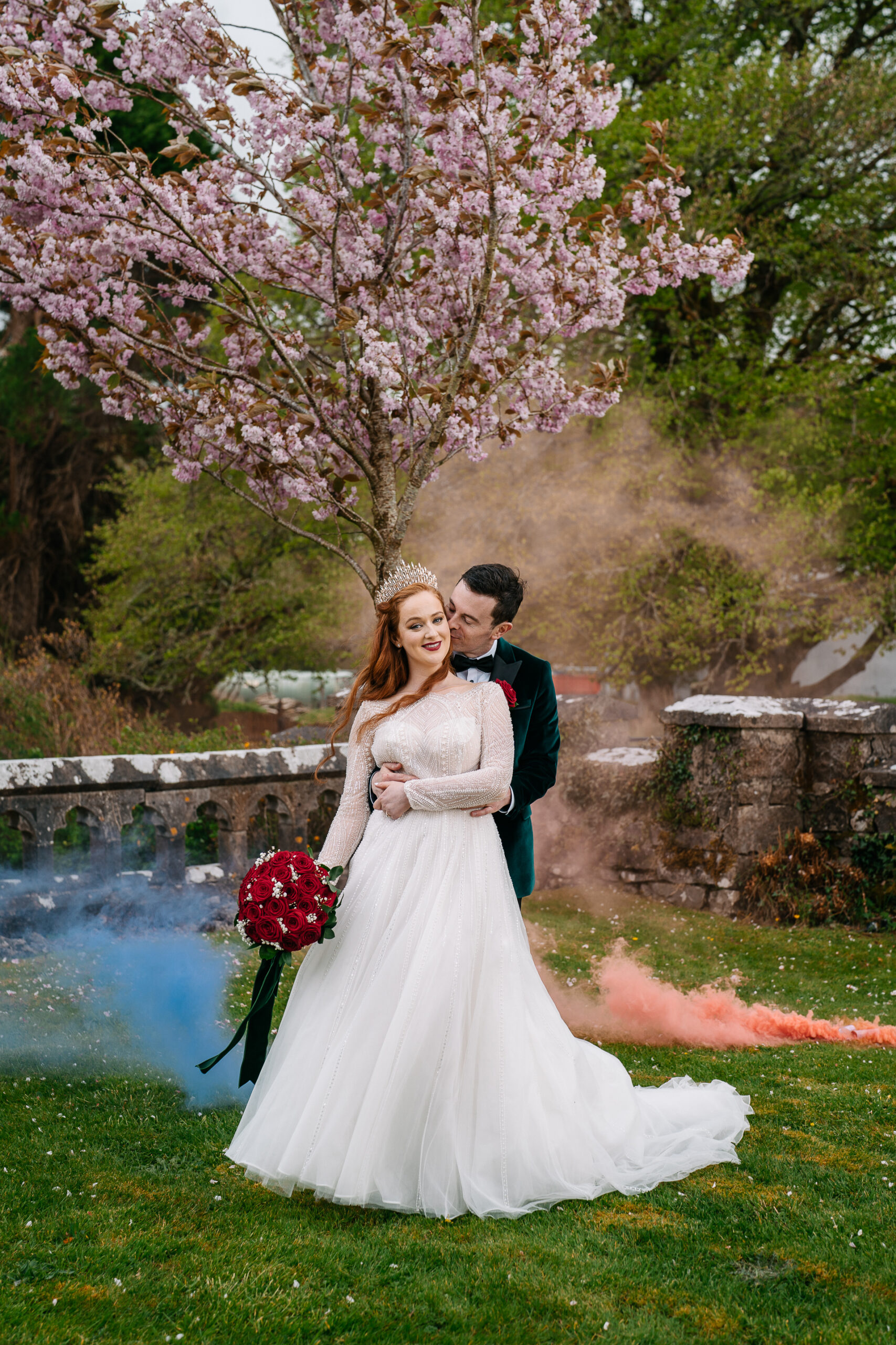 Bride and groom under cherry blossom tree with smoke effects during