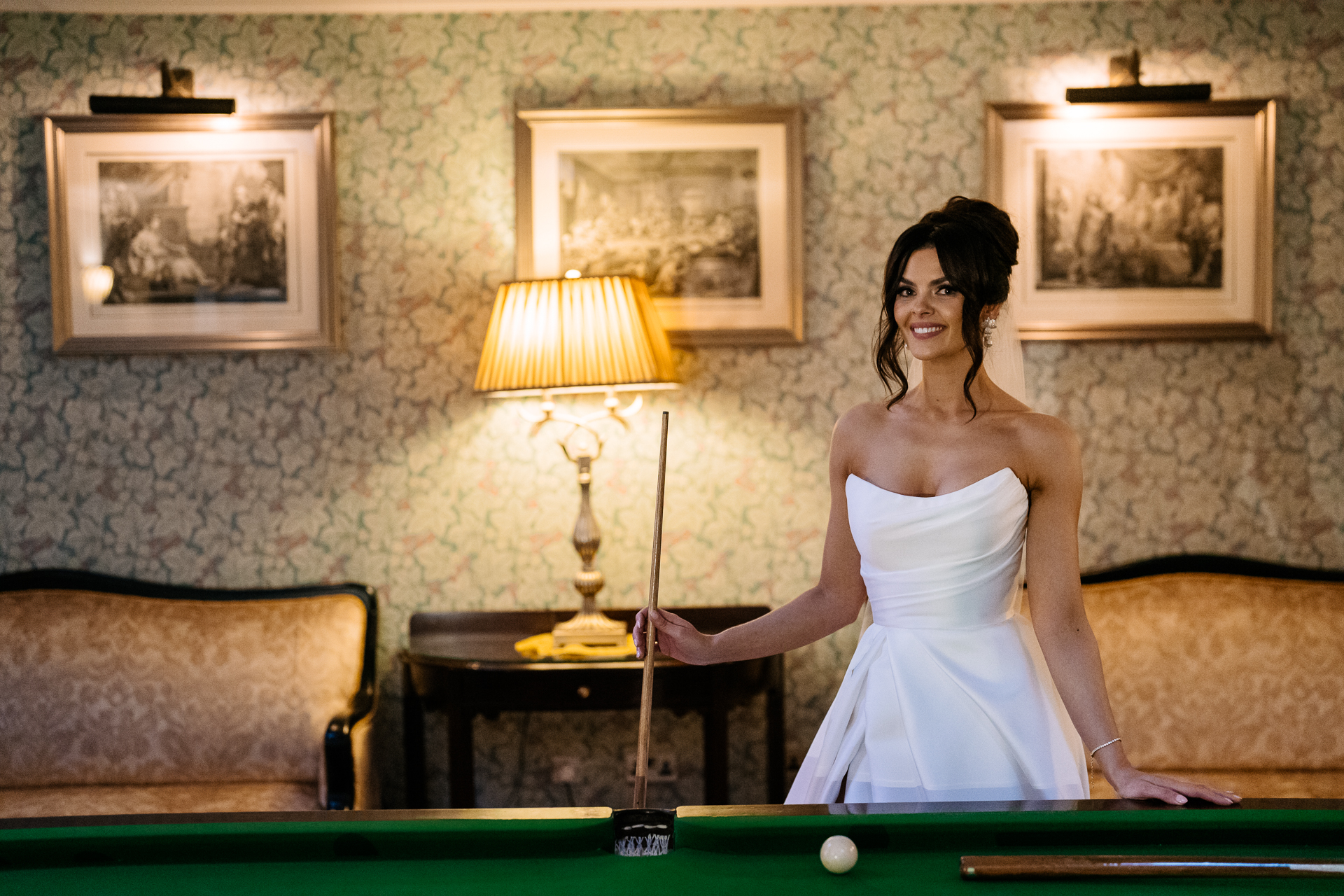 Bride standing in the Snooker Room of Markree Castle, next to a lamp and mirror