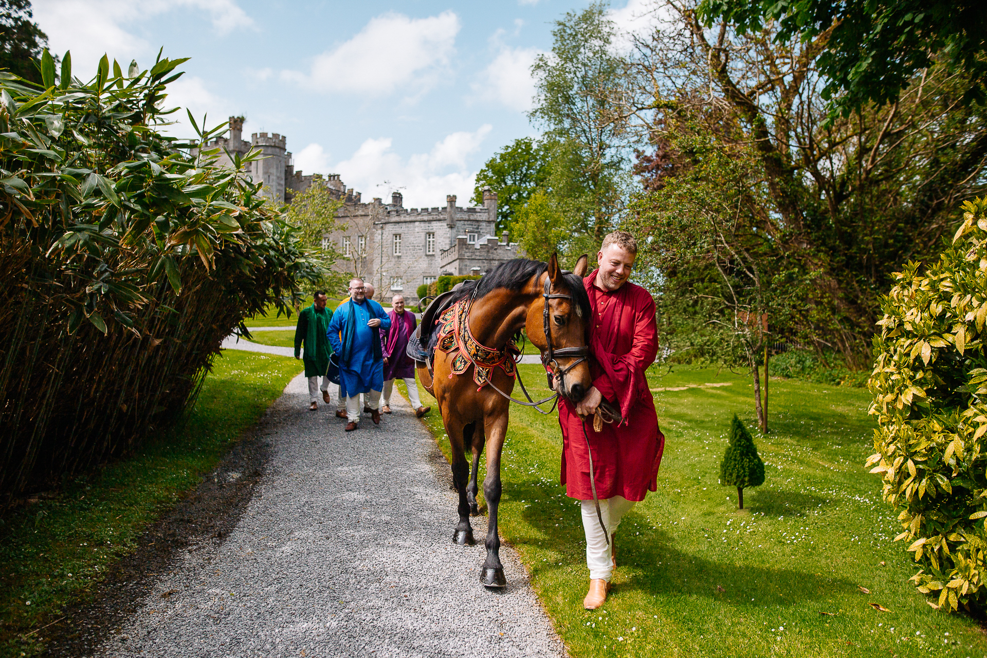 Indian groom arriving on horseback during a traditional Baraat procession at Markree Castle wedding in Ireland
