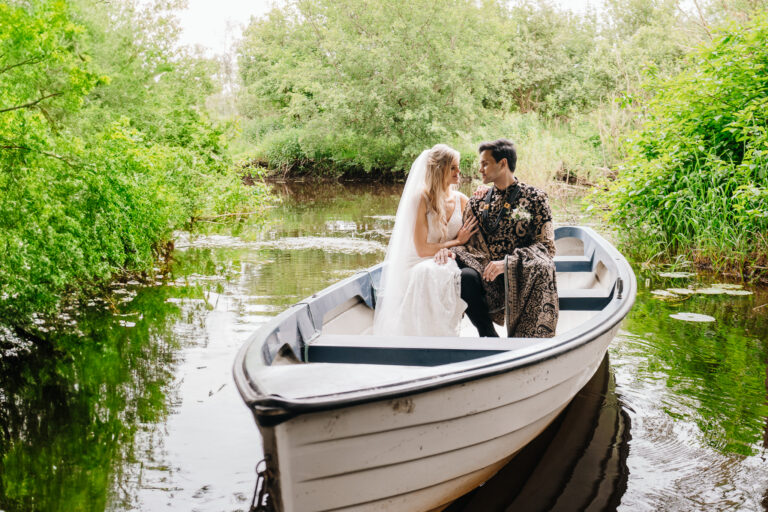 Bride and groom in a boat at Markree Castle surrounded by lush green garden – romantic wedding portrait by Irish wedding photographer.