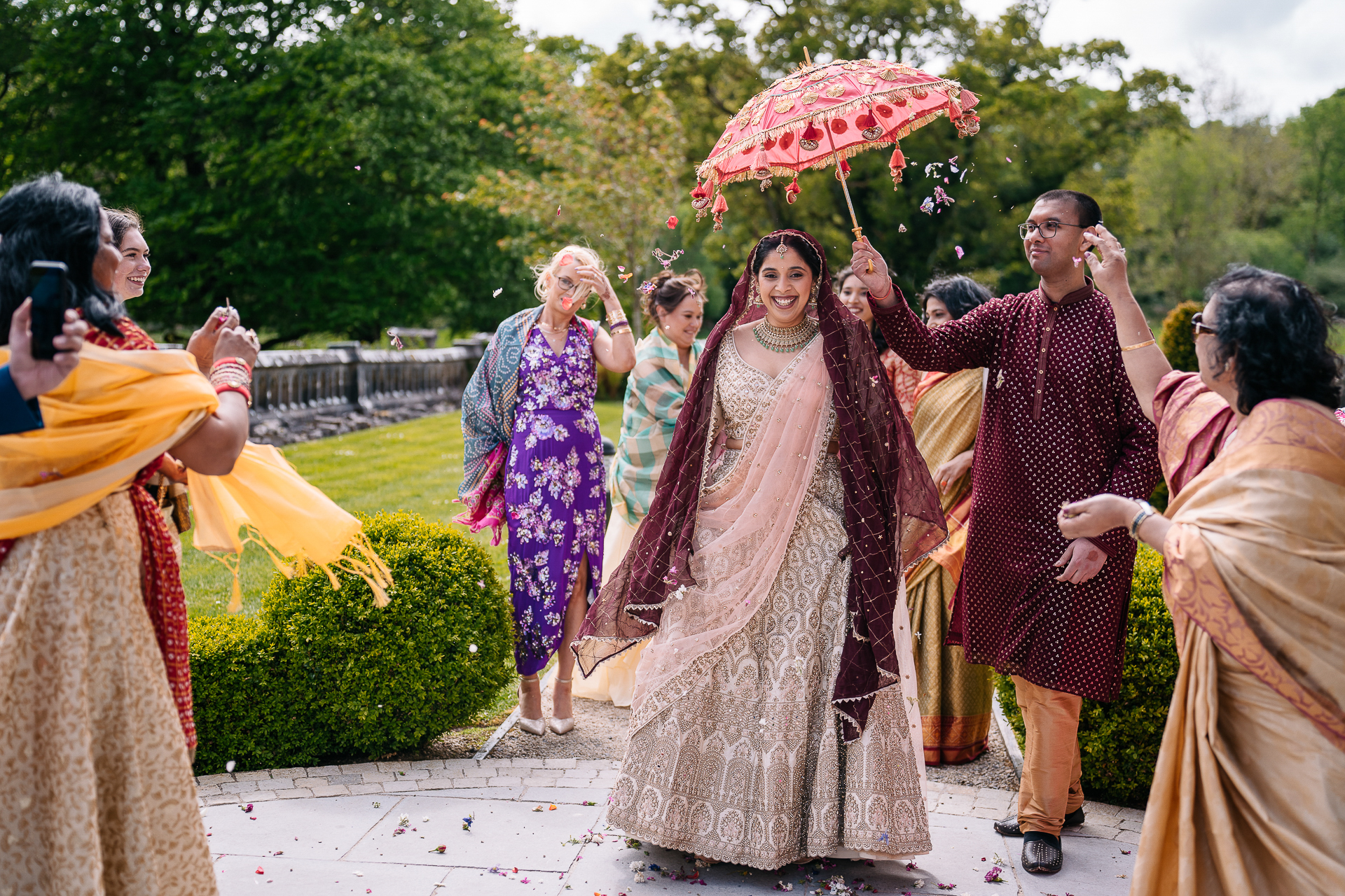 Indian bride walking to the Mandap under a red parasol during Markree Castle wedding ceremony