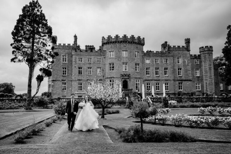 Bride and groom walking through the garden in front of Markree Castle in Ireland – a classic black and white photo by a Dublin Wedding Photographer.