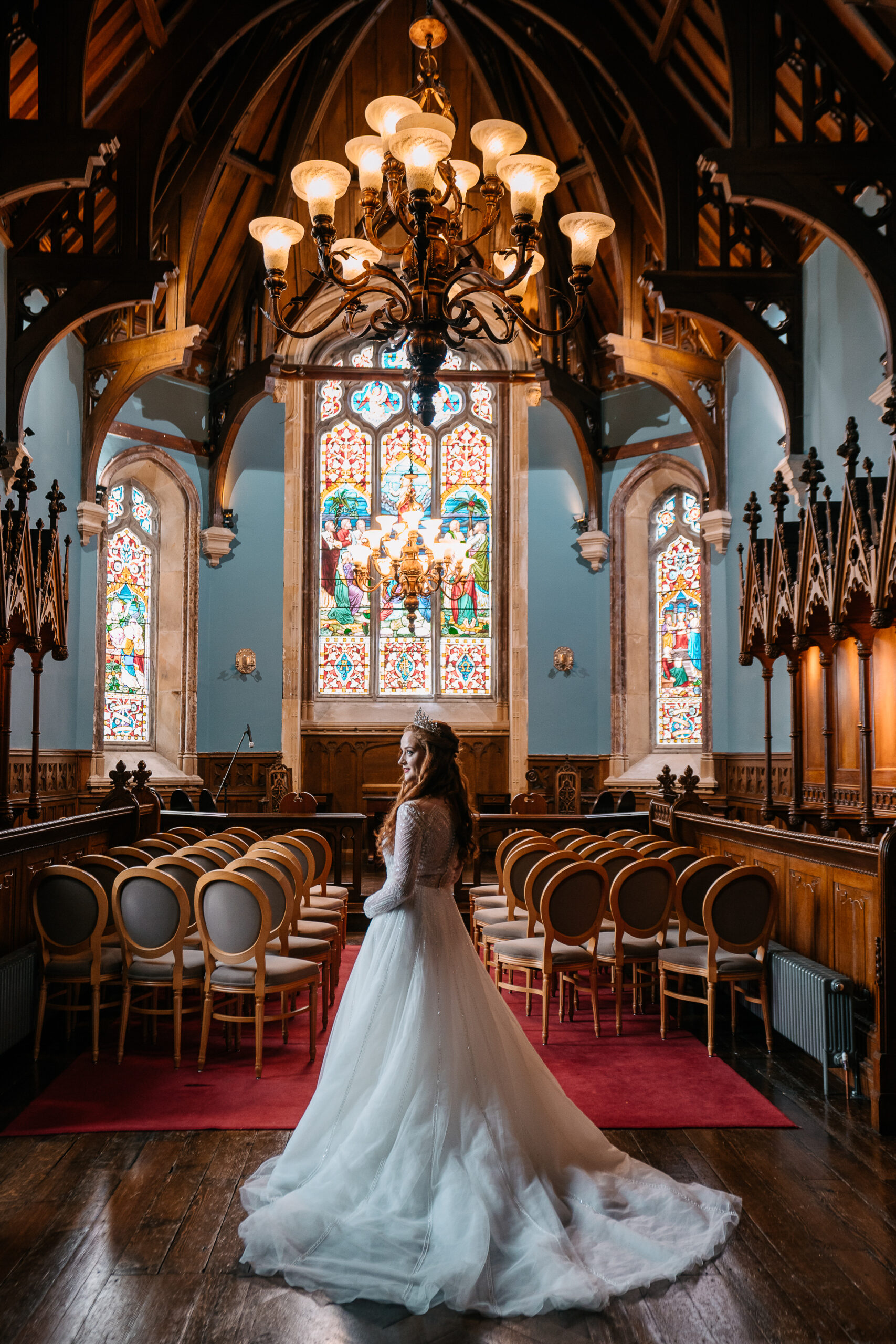 Bride standing in front of stained-glass windows and chandelier inside the chapel at Markree Castle – a romantic bridal portrait full of depth and Irish elegance.