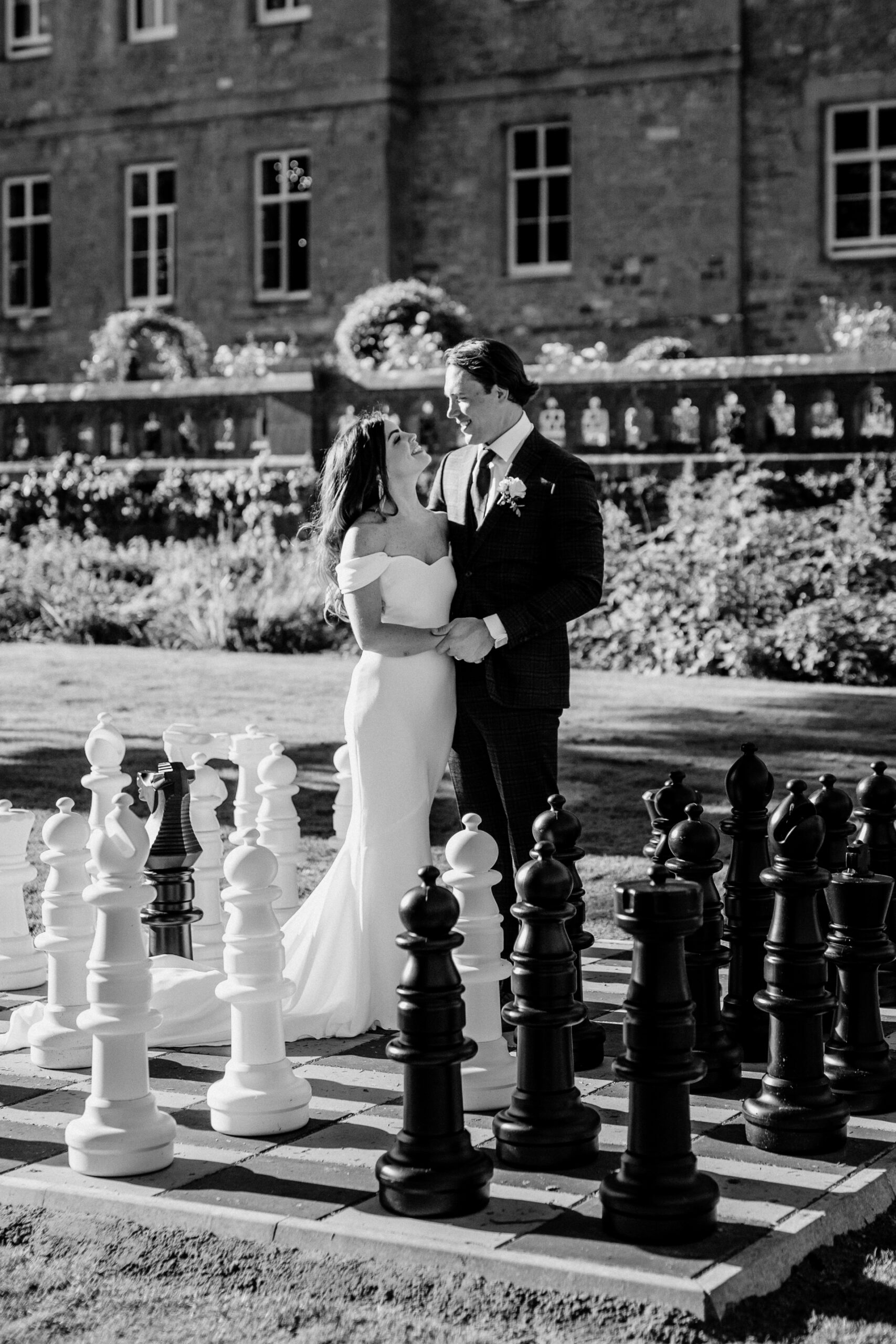 Bride and groom kissing on giant chessboard outside Markree Castle – elegant black and white wedding portrait