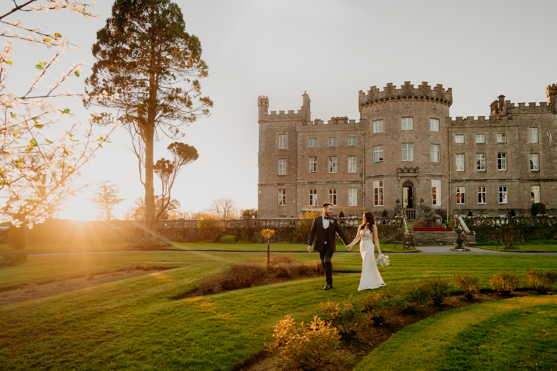 Bride and groom walking at sunset in front of Markree Castle – romantic golden hour portrait during an outdoor wedding in Ireland