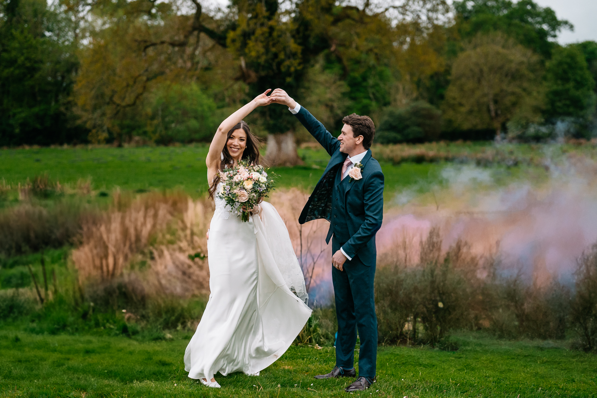 Bride and groom dancing together surrounded by pink smoke in the gardens of Markree Castle