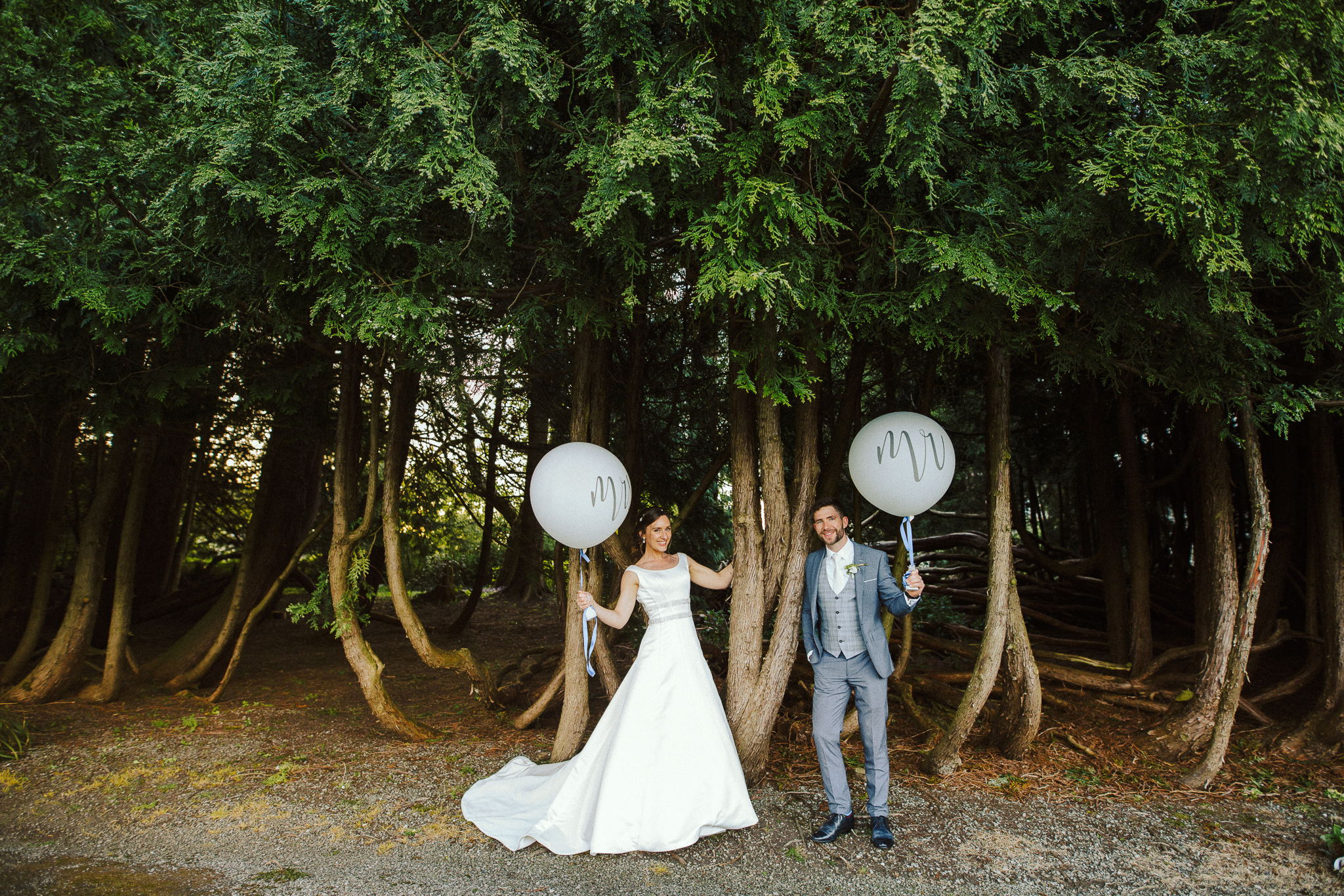 Bride and groom holding white balloons during a forest wedding session at Markree Castle.
