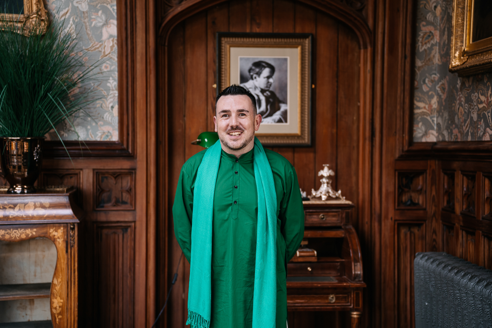Groomsman wearing a green kurta standing in a wood-panelled hallway at Markree Castle wedding