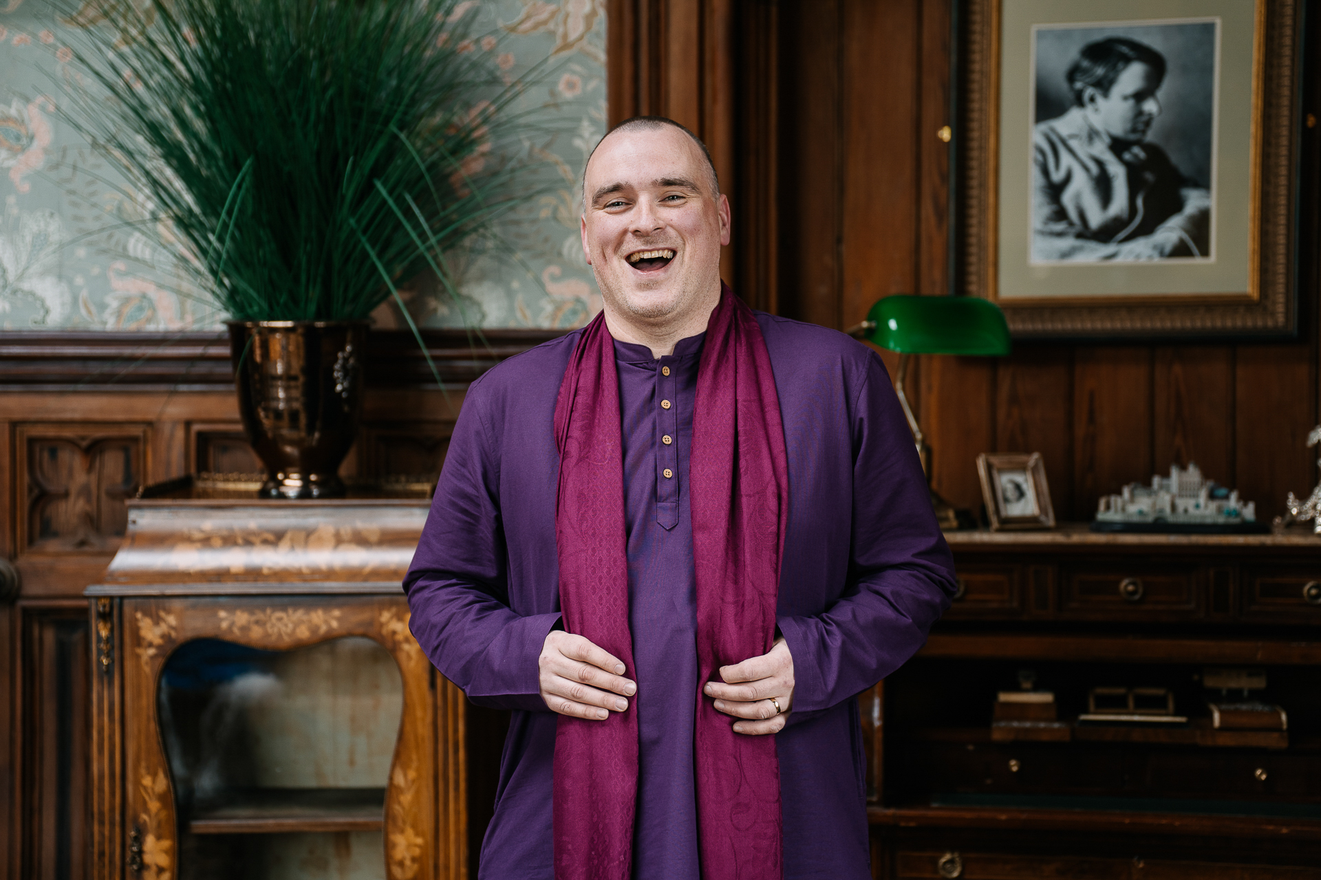 Groomsman in a purple kurta smiling confidently in the wood-panelled library of Markree Castle wedding